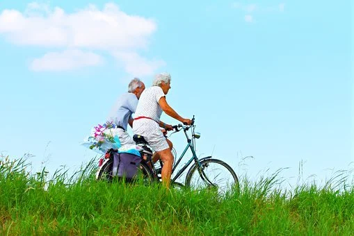 two people riding bikes along a grassy path