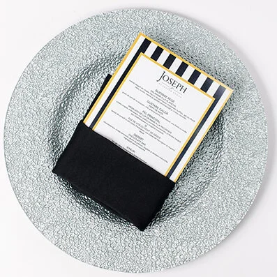 Invitation card wrapped partially in black envelope on a textured glass plate