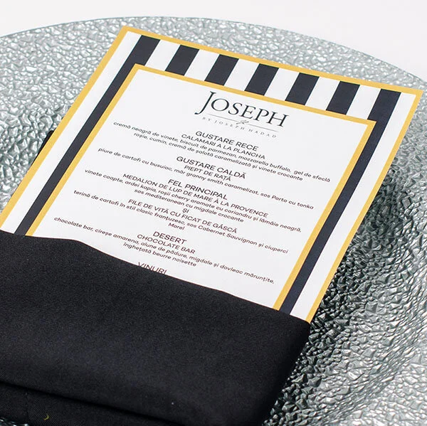 Restaurant menu with black and white striped border placed on a textured silver surface