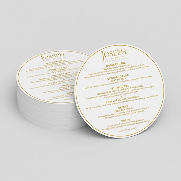 Stack of white circular menu coasters with gold text listing various dishes and beverages.