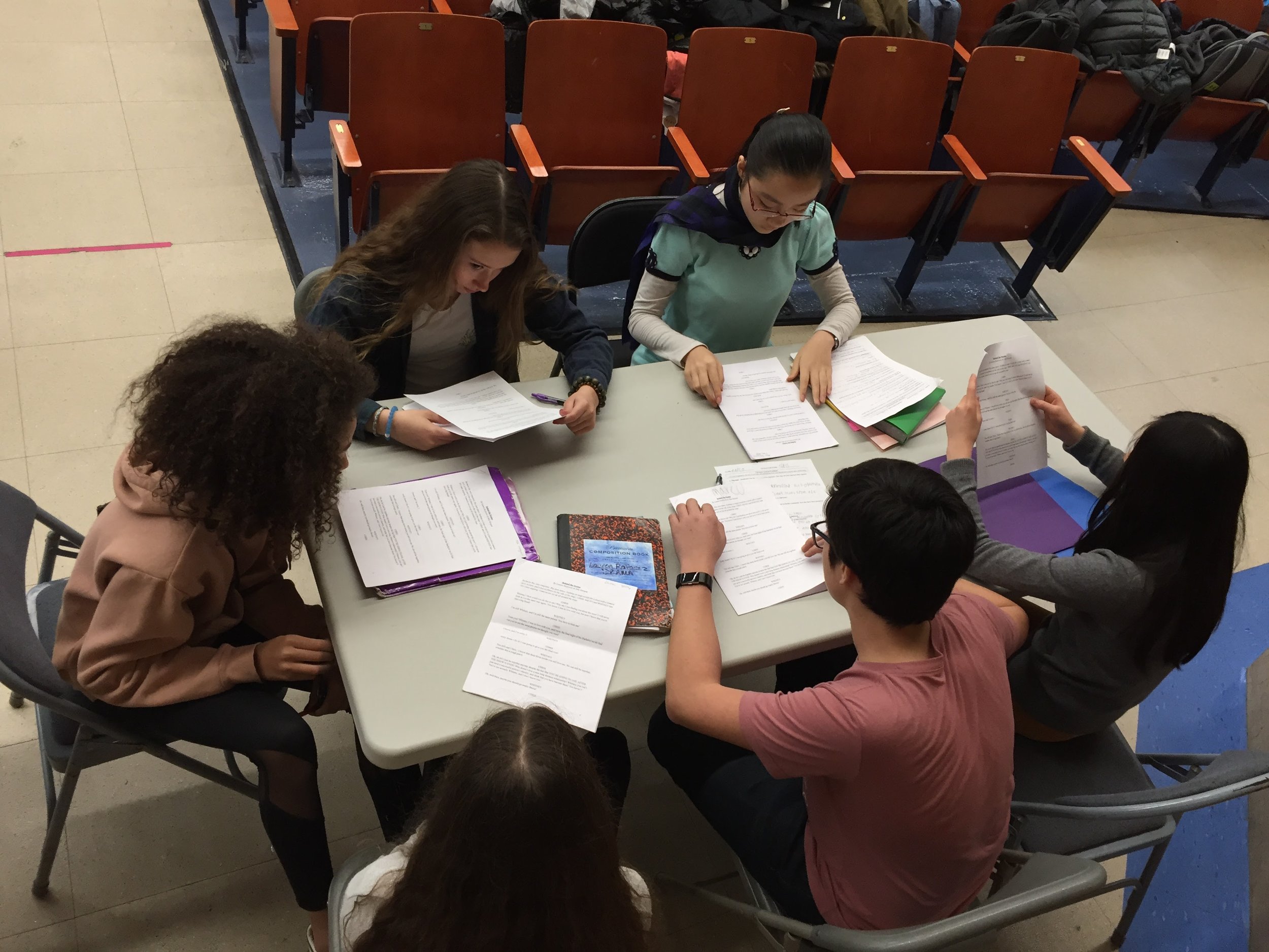  students sit around a table reading a play 