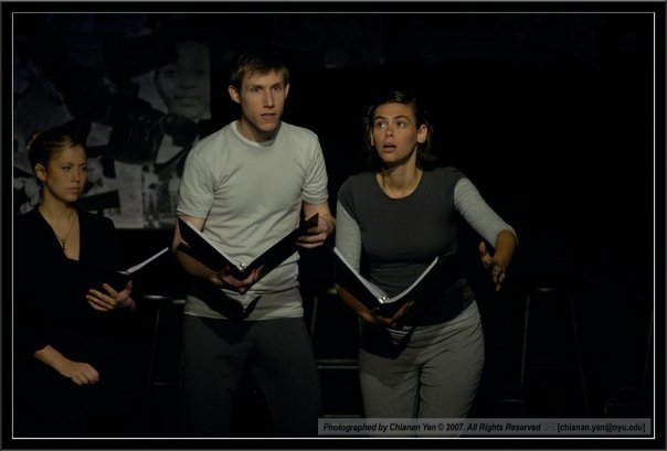  two actors (one male, one female- Aliza) dressed in grey and holding scripts, look up to the sky with shock and wonder 