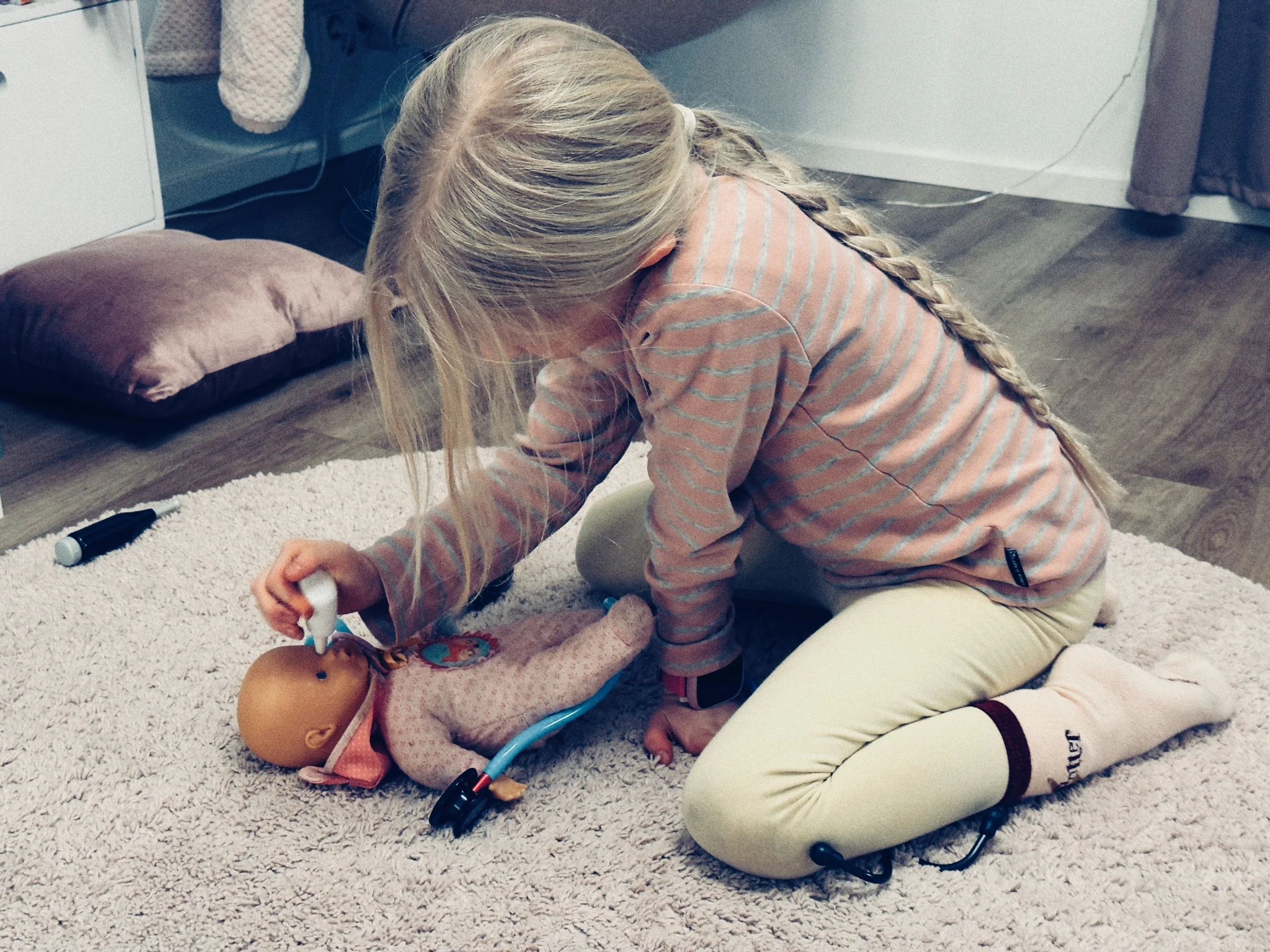 Kuvassa lapsi leikkii lääkäriä ja tutkii vauvaa.