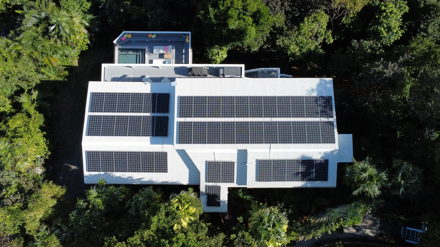 Aerial view of Vela Vista’s roof lined with solar panels, surrounded by tropical forest