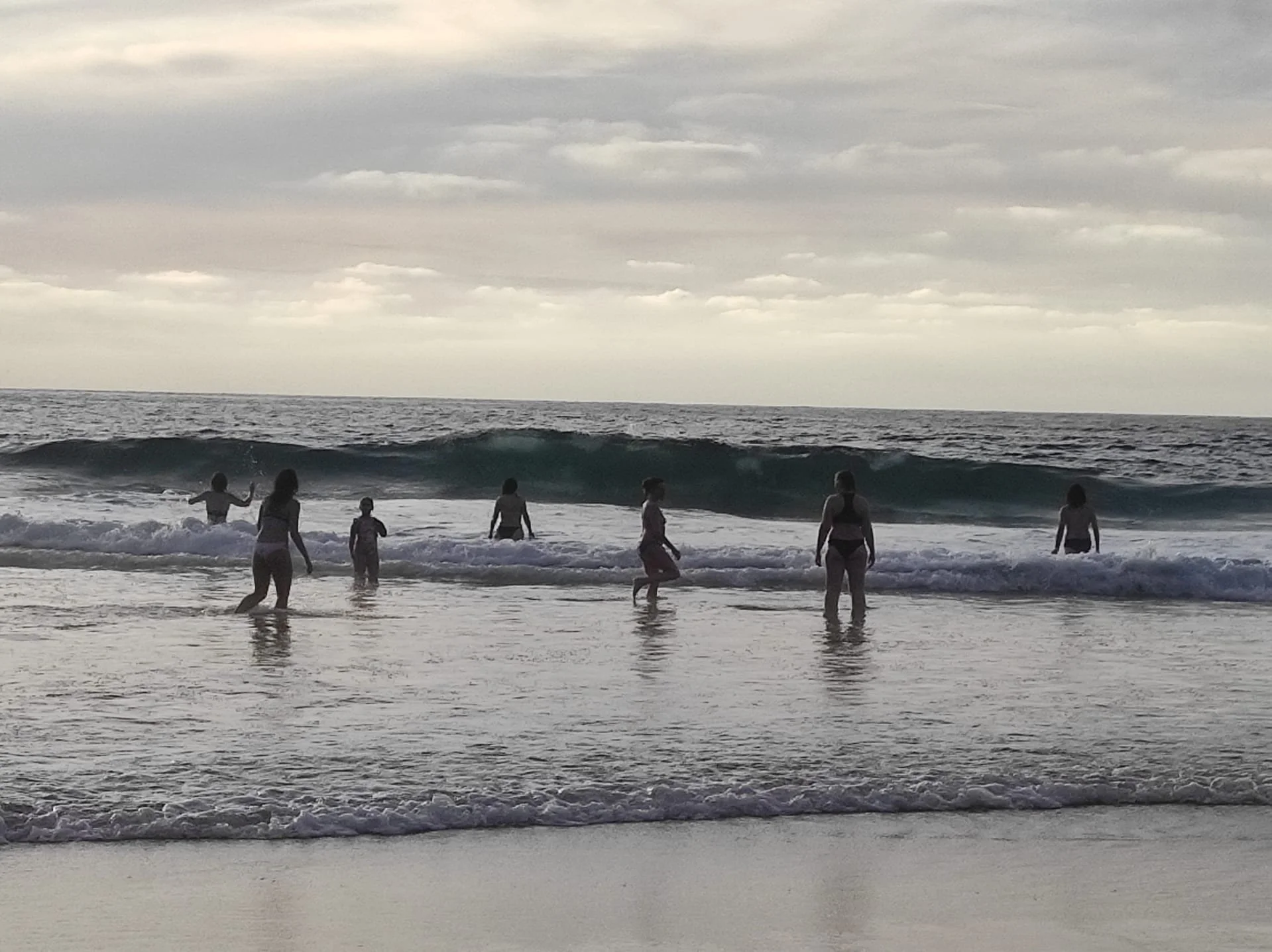Frauen gehen gemeinsam auf eine Ozeanwelle zu. Verbundenheit.