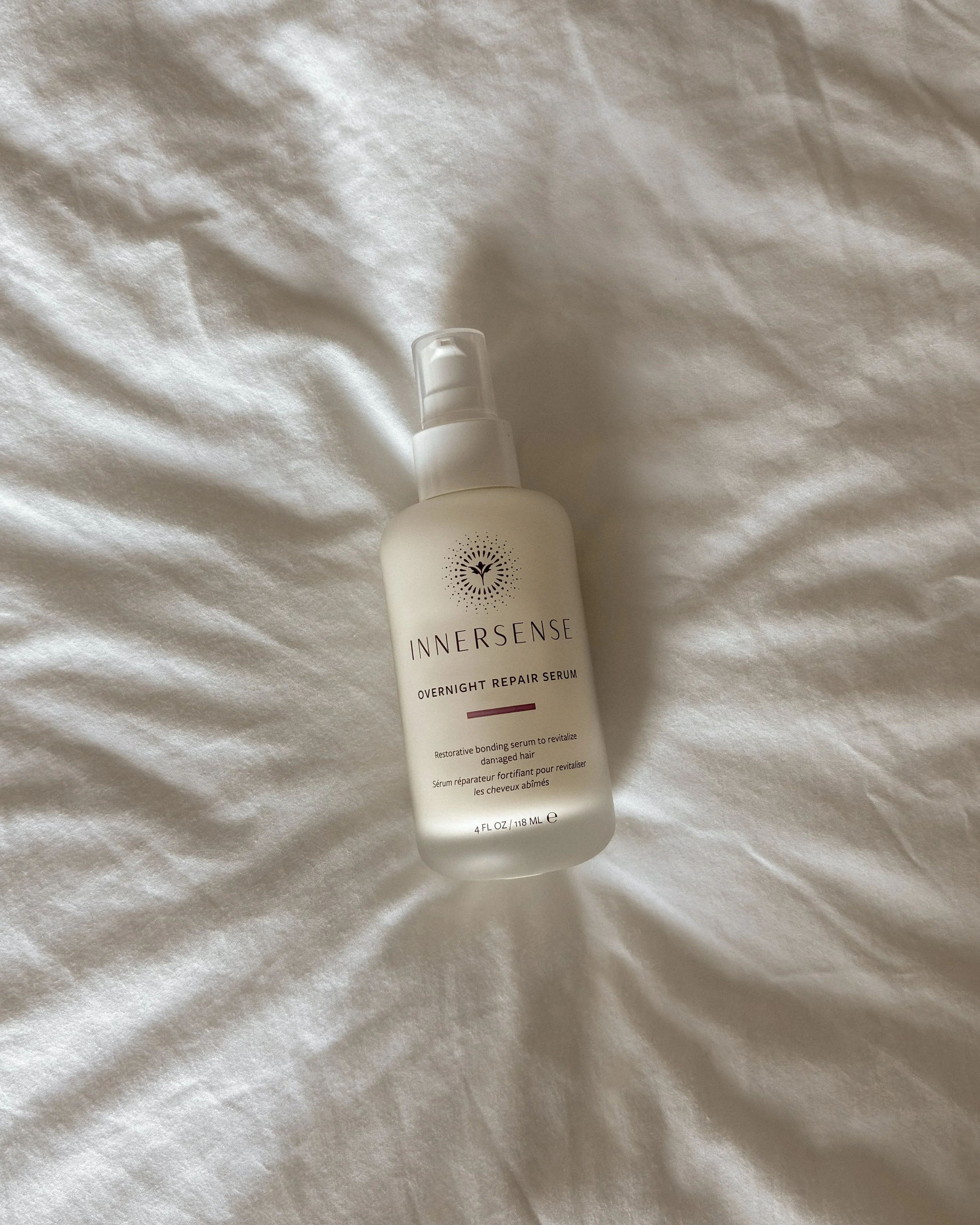 Innersense Overnight Repair Serum resting on white bedding in soft natural light.