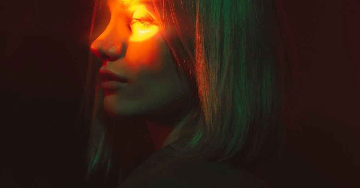 Dramatic portrait lit by a single continuous LED light in a dark studio, showing the moody strobe vs continuous lighting look