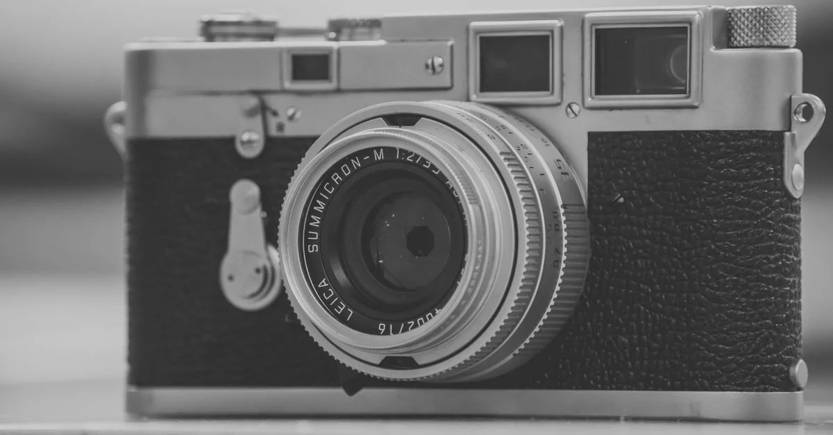 Black Friday camera deals 2026: evaluating a rangefinder camera on a desk before buying, checking the deal against real value
