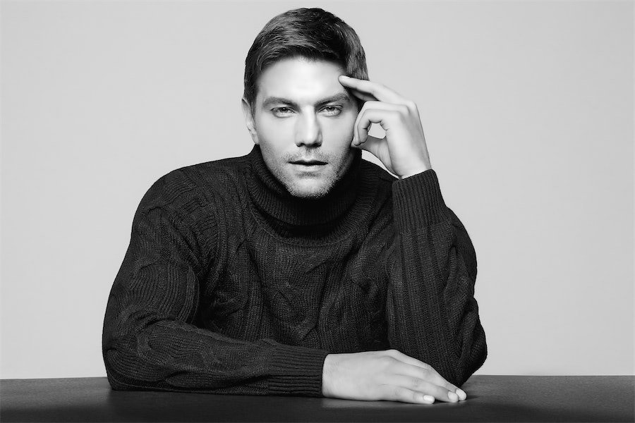 Photographer demonstrating posing techniques for a men's portrait session