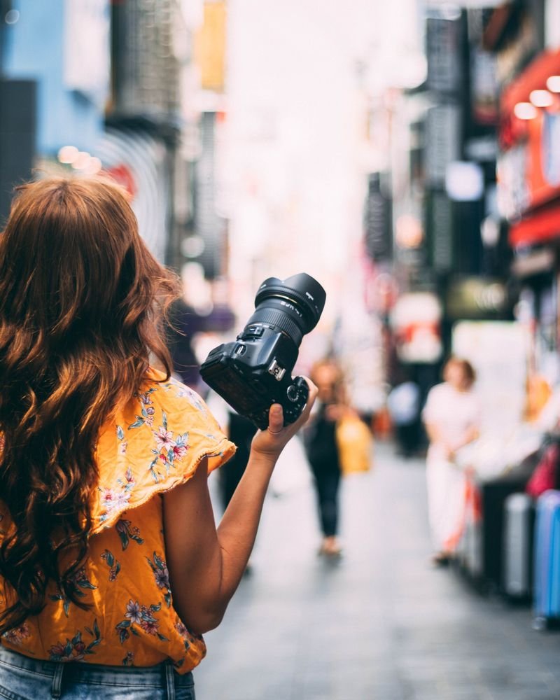 Photographer holding a camera while walking down a busy city street, the carry-everywhere habit behind the best cameras for street photography