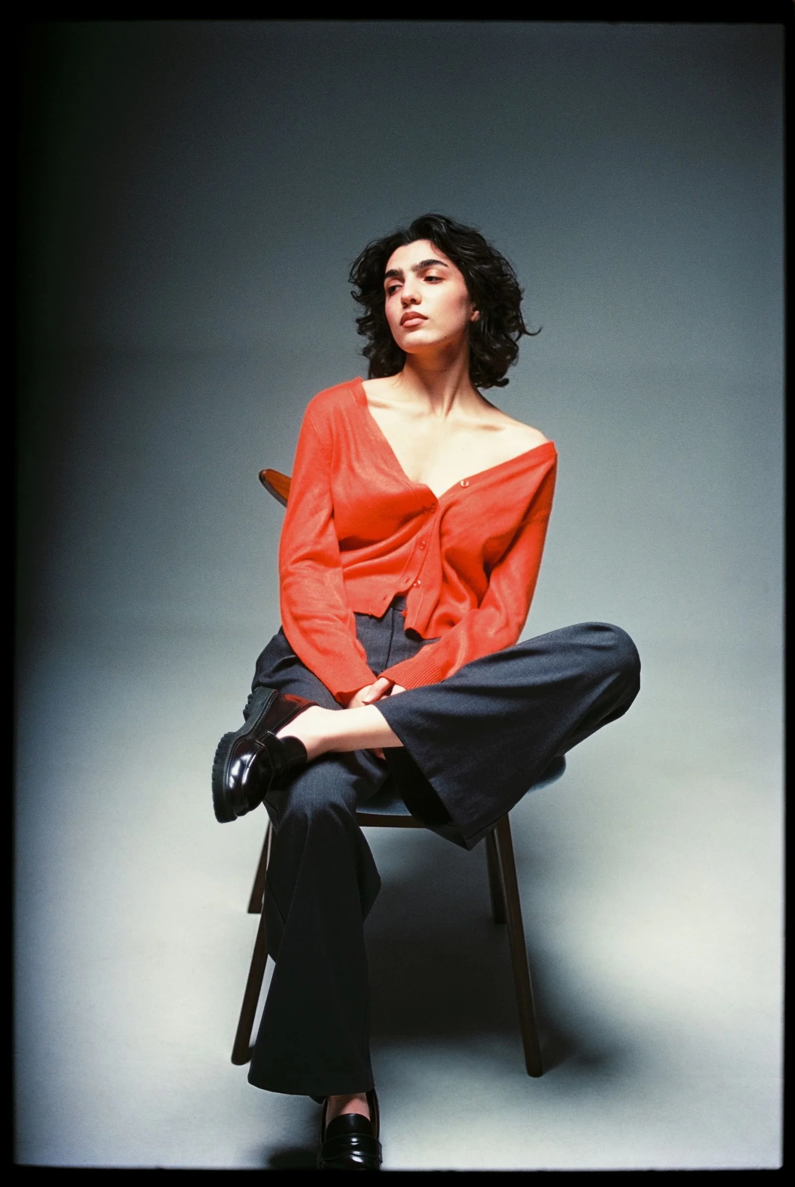 Editorial fashion photograph of a woman in a red cardigan posing in a Los Angeles studio