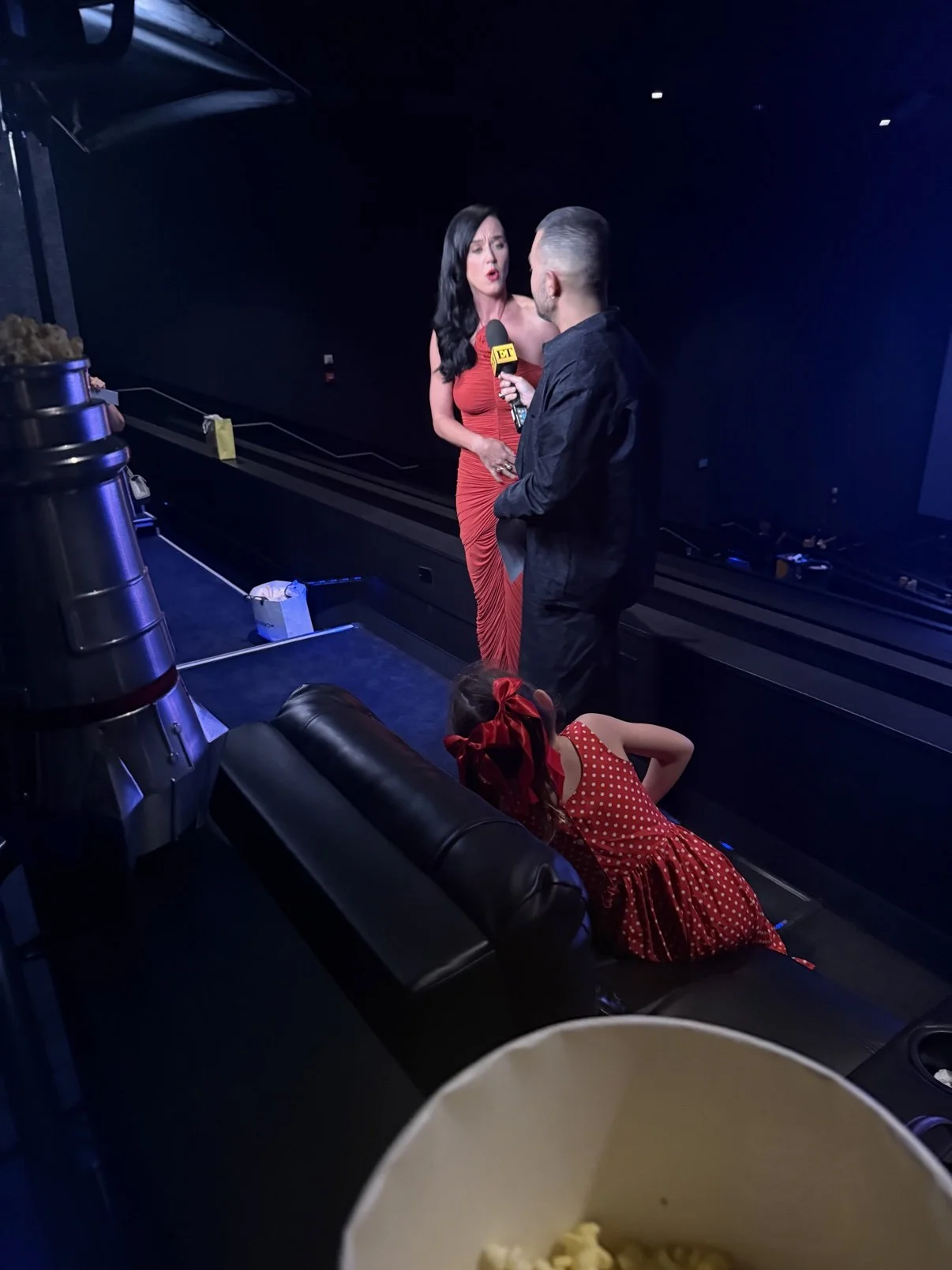 Katy Perry in a red gown being interviewed backstage at her concert documentary event