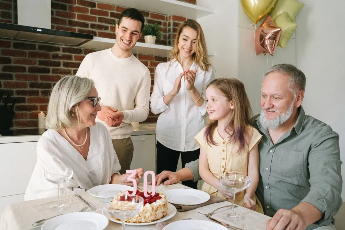 Multi-generational family celebrating together around a birthday cake