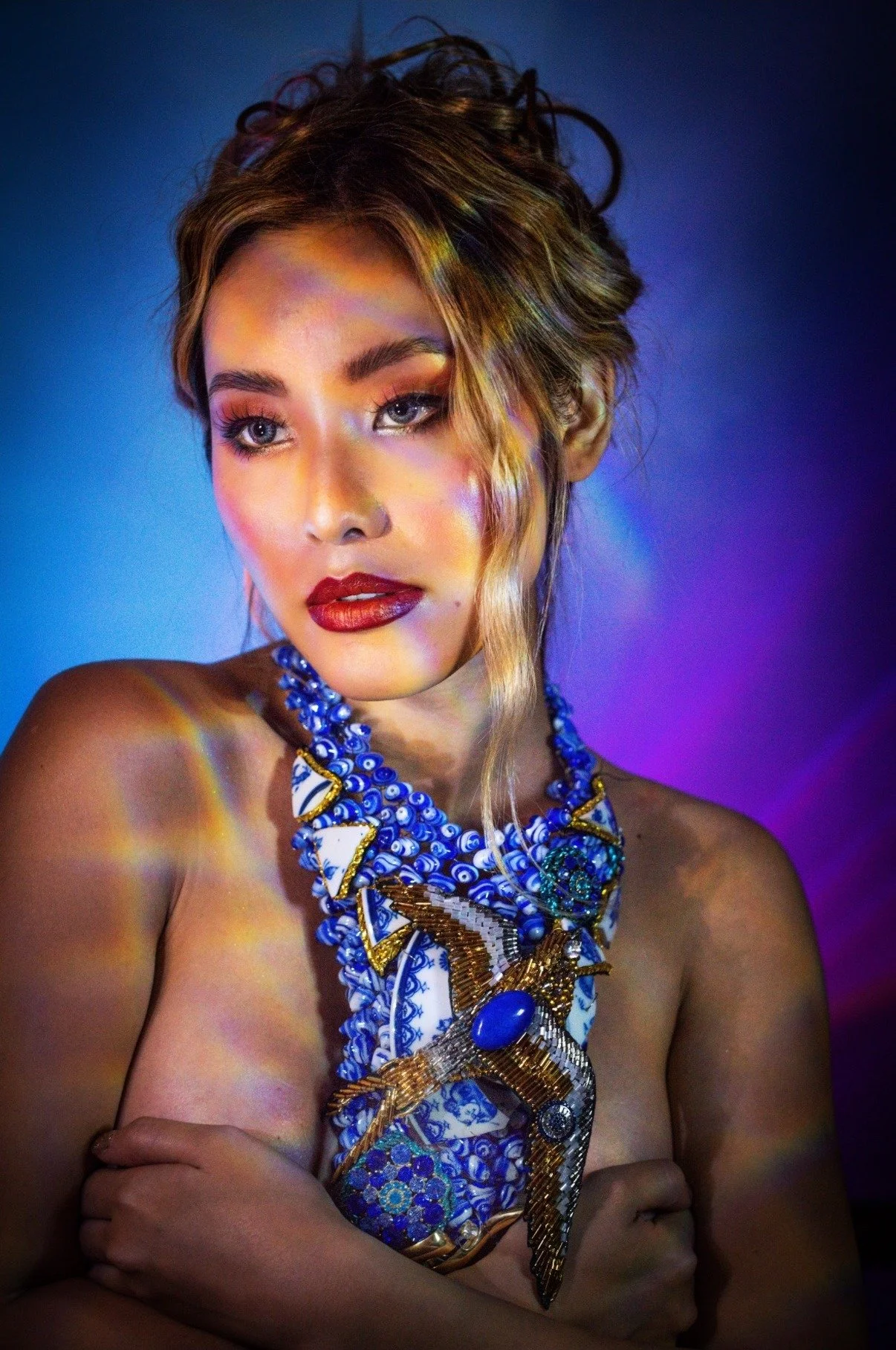 Model wearing an elaborate blue and gold statement necklace in a dramatic editorial jewelry portrait by David Christopher Lee