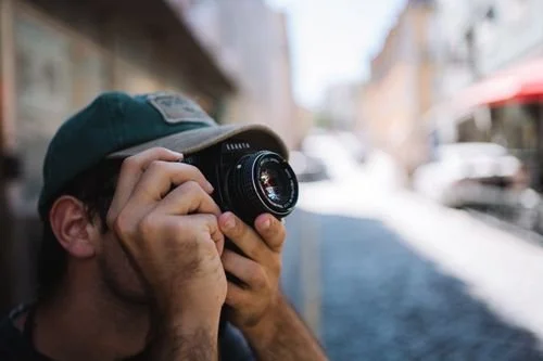 Street photographer shooting with a compact camera on a city street, one of the best cameras for street photography in hand