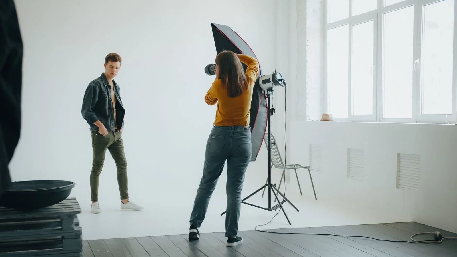 Photographer lighting a studio portrait on set, where clean light reduces retouching work later