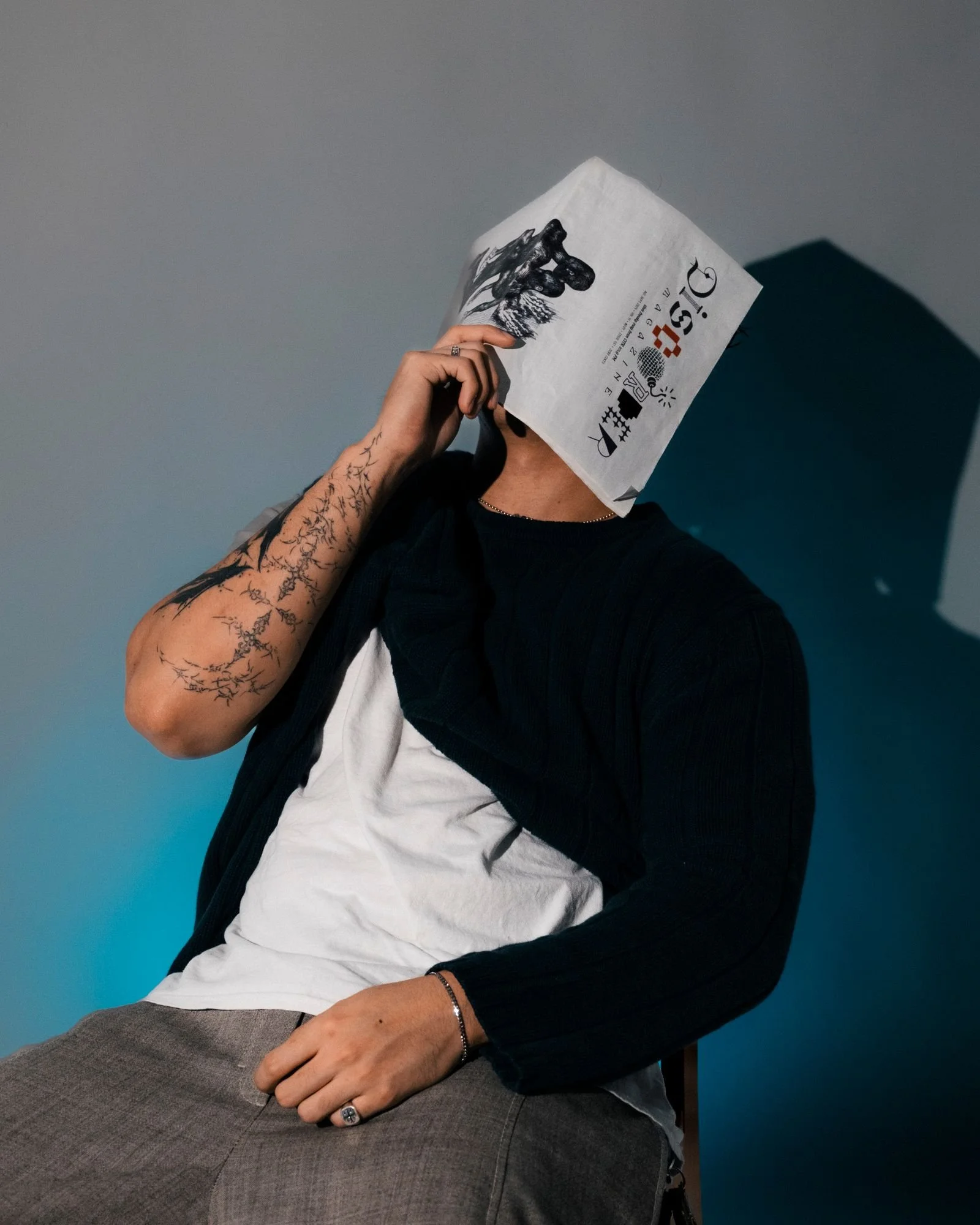 Editorial portrait of a tattooed model reading a newspaper in a Los Angeles studio