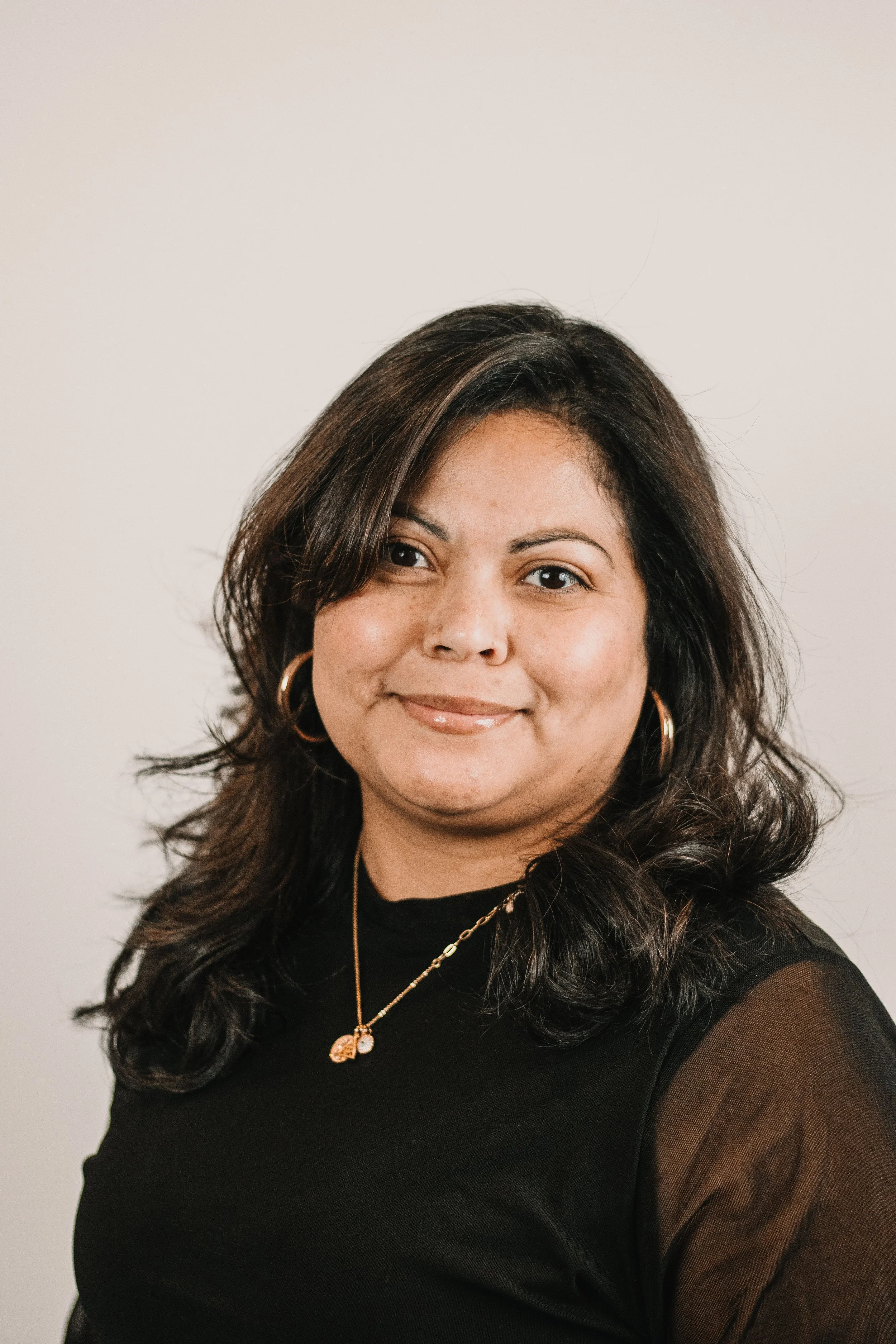 Professional headshot of a confident woman in tailored attire with warm expression