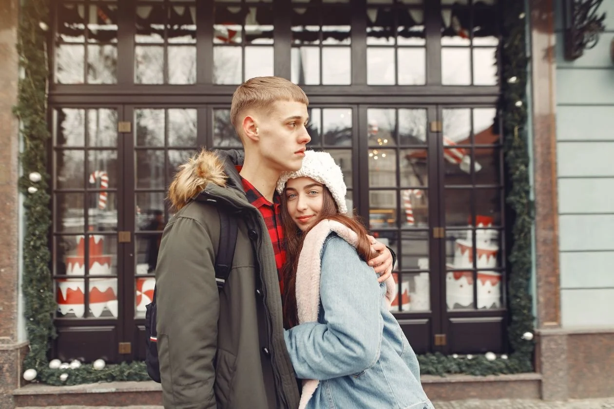 Young couple embracing in front of a decorated storefront during a casual Los Angeles engagement photo session