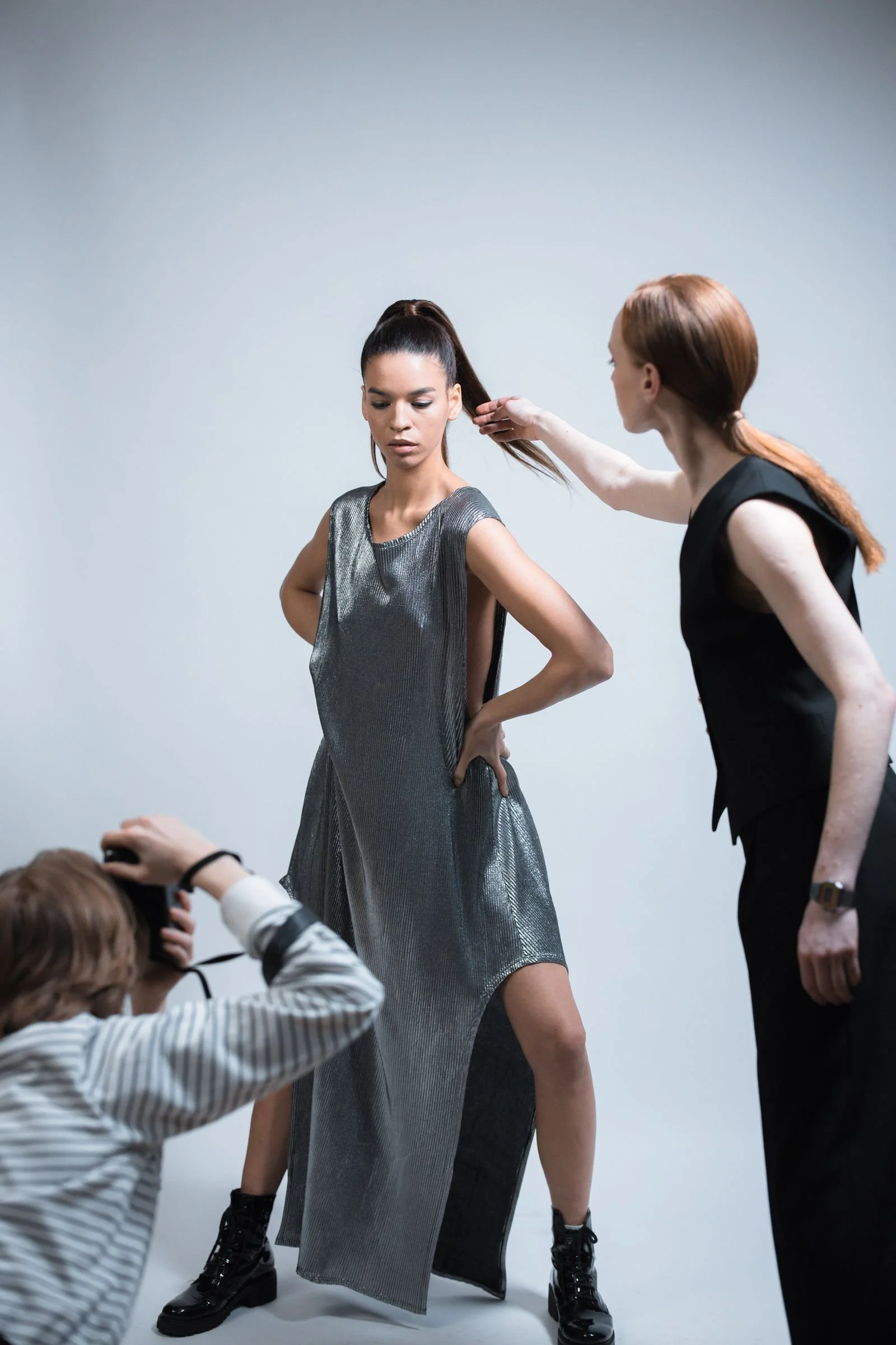 Fashion campaign photoshoot in a Los Angeles studio with stylist adjusting the model