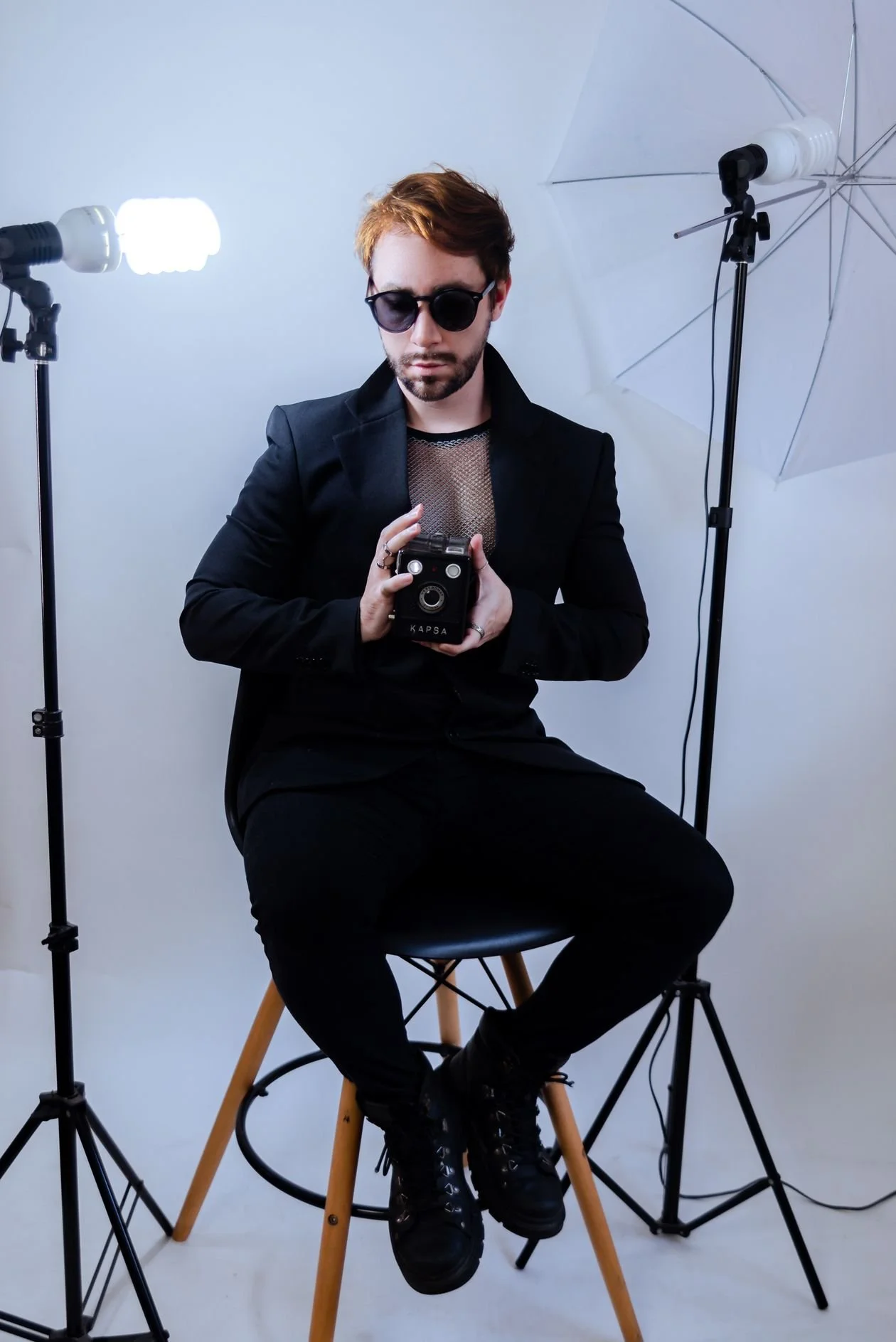 Photographer holding a camera in a studio with professional lighting equipment