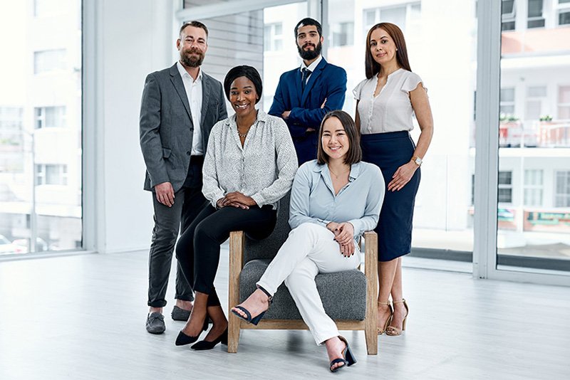 Smiling business team of five posing together in a bright modern office