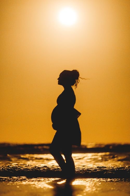 Pregnant woman in silhouette at golden hour cradling her baby bump, Los Angeles maternity photography