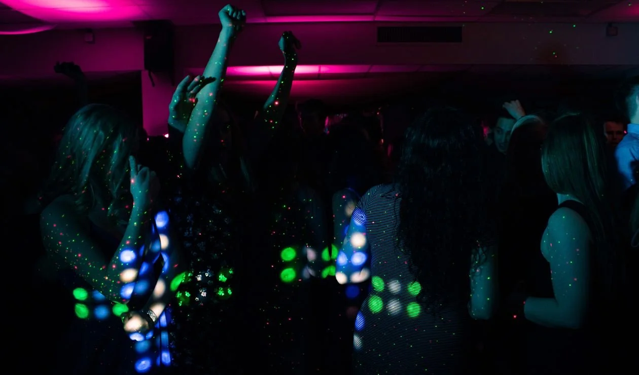 Guests dancing under colorful DJ lighting on a dark dance floor at a bar mitzvah party