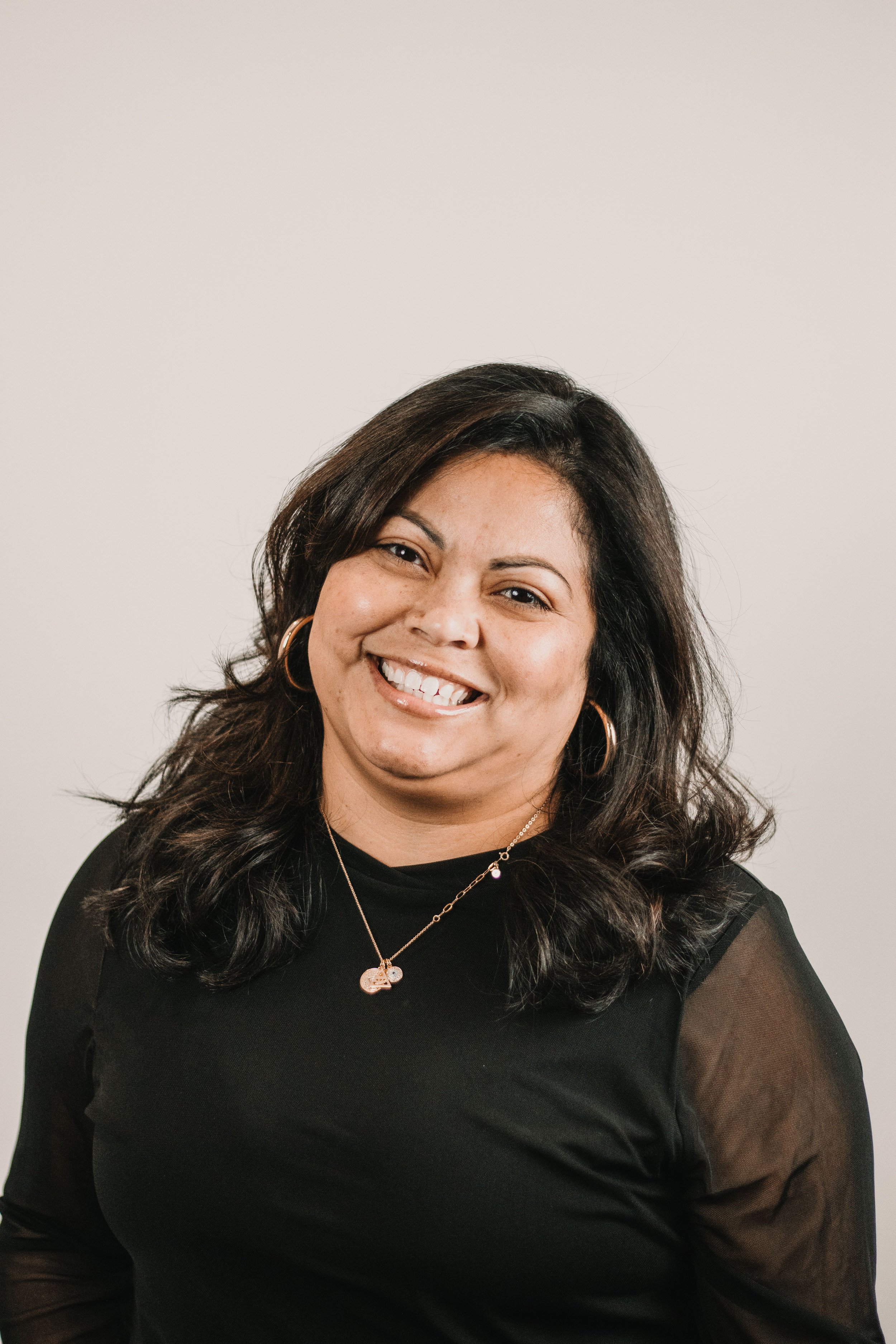 Professional female headshot in Los Angeles, smiling woman in black top against clean backdrop