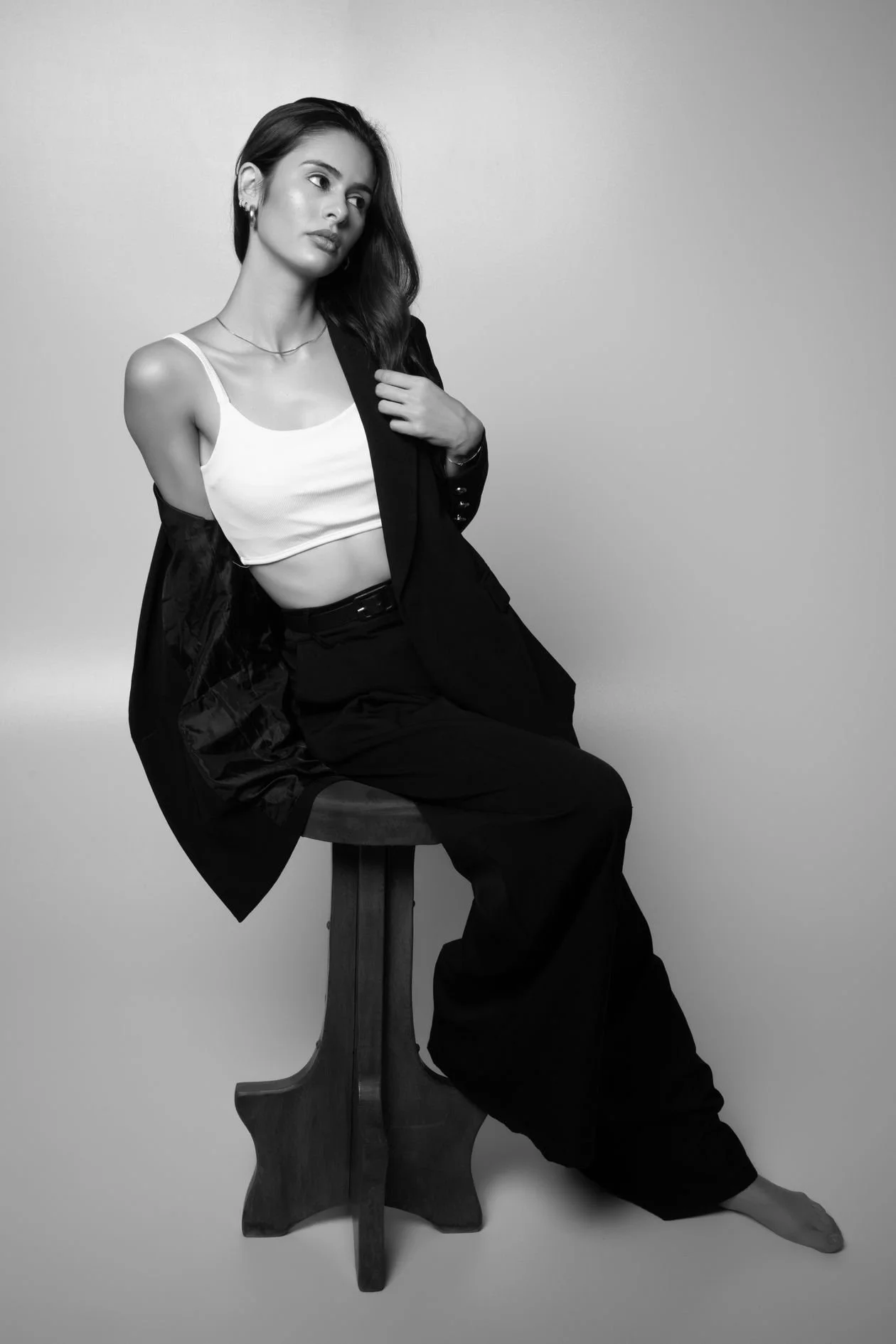 Black and white editorial portrait of a seated model in a directed fashion pose
