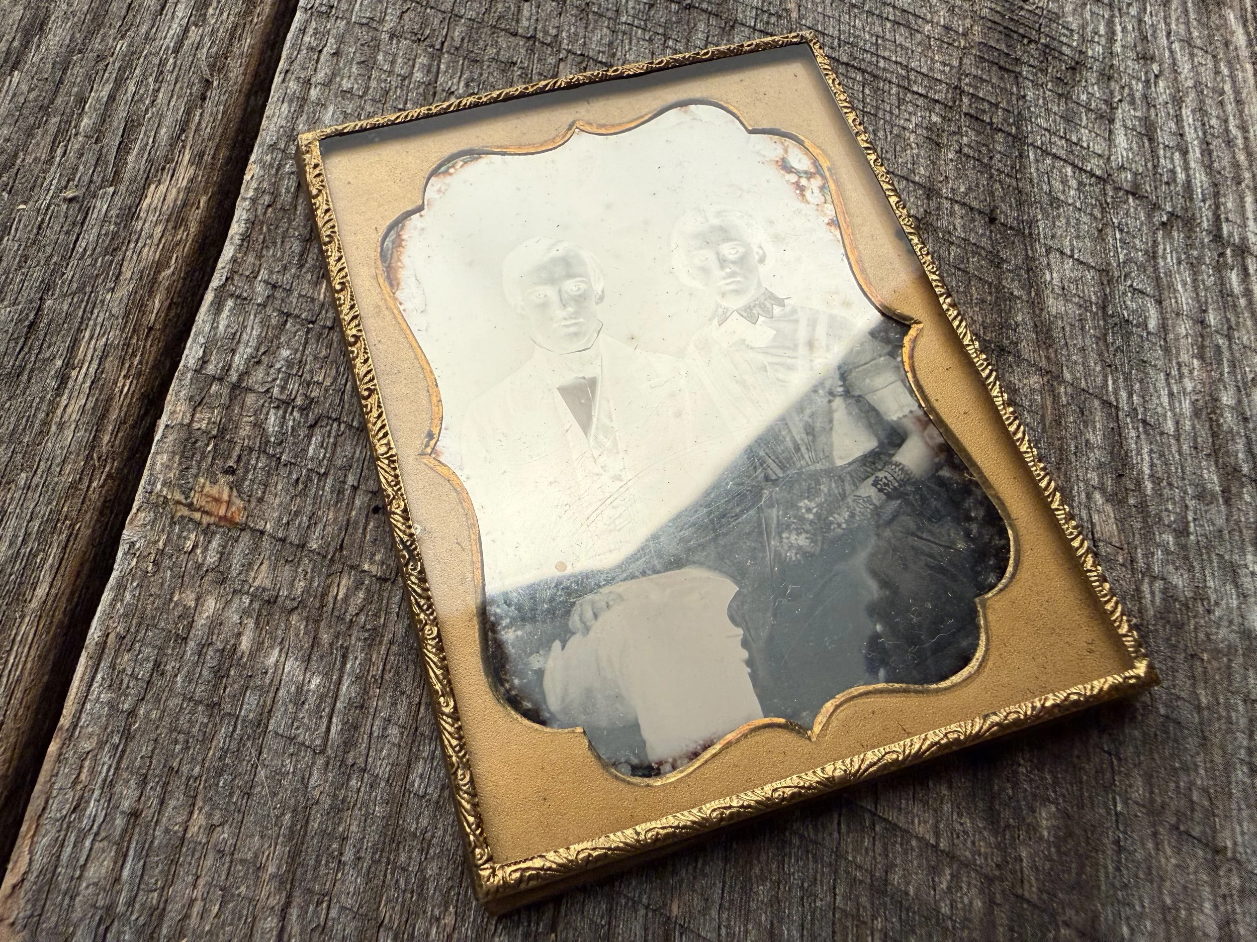 A historical daguerreotype held at an angle showing its mirror-like silver surface and the way the image shifts between positive and negative