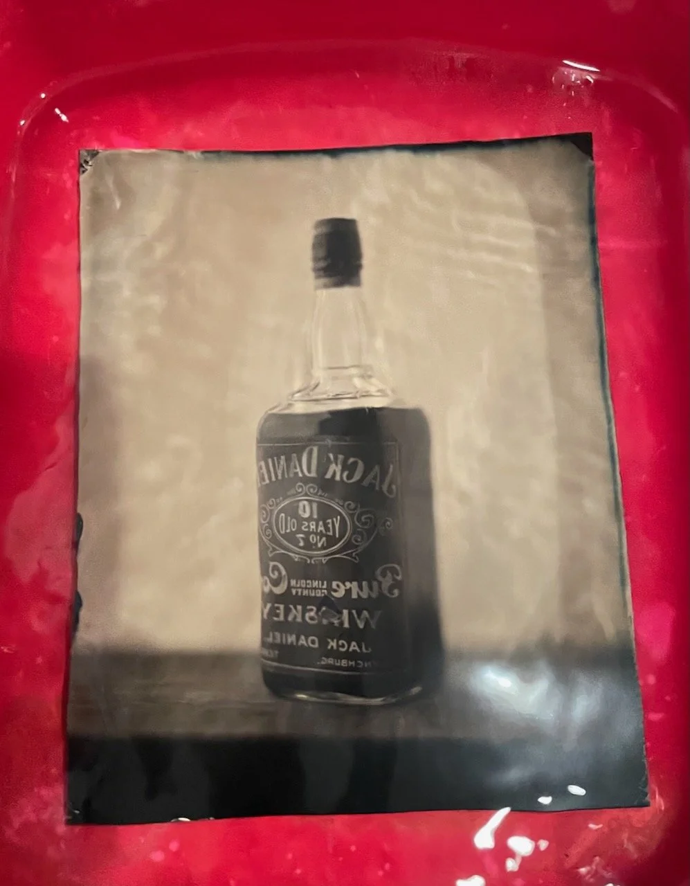 Behind the scenes of tintype photography, collodion plate being washed in the bath.