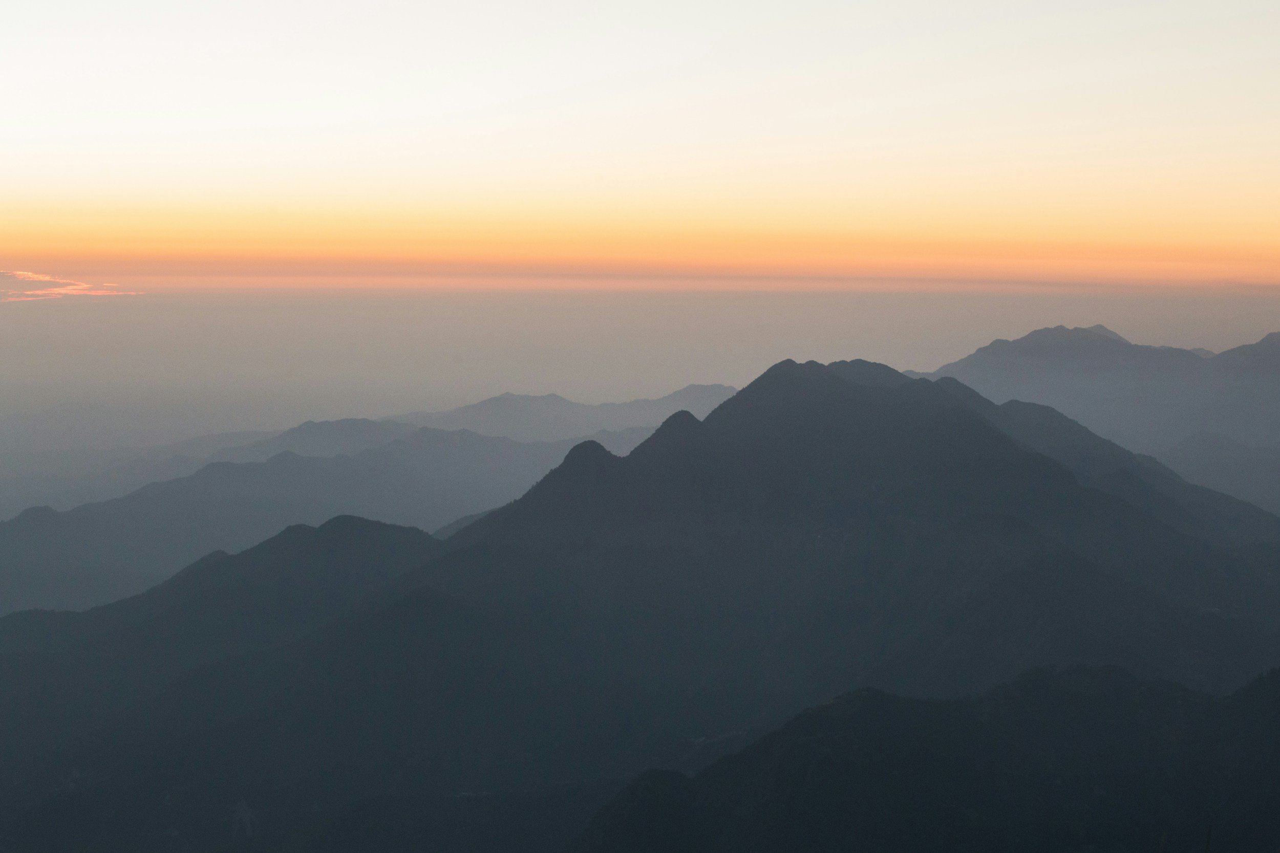 Layered mountain ranges fading into the distance at sunset, symbolising long-term perspective and working across time horizons.