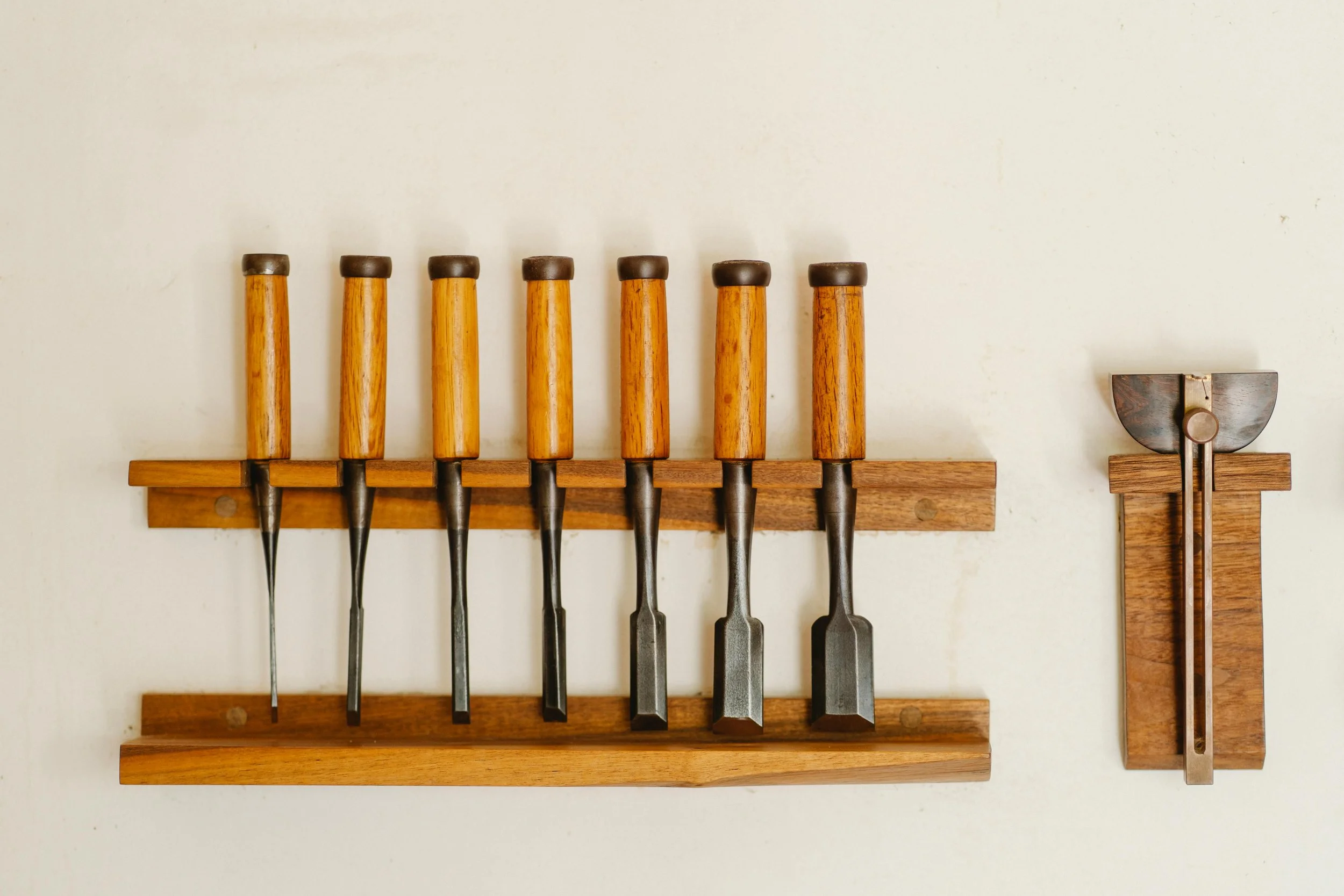 Woodworking tools hanging on a workshop wall, representing craftsmanship, skill and disciplined craft.