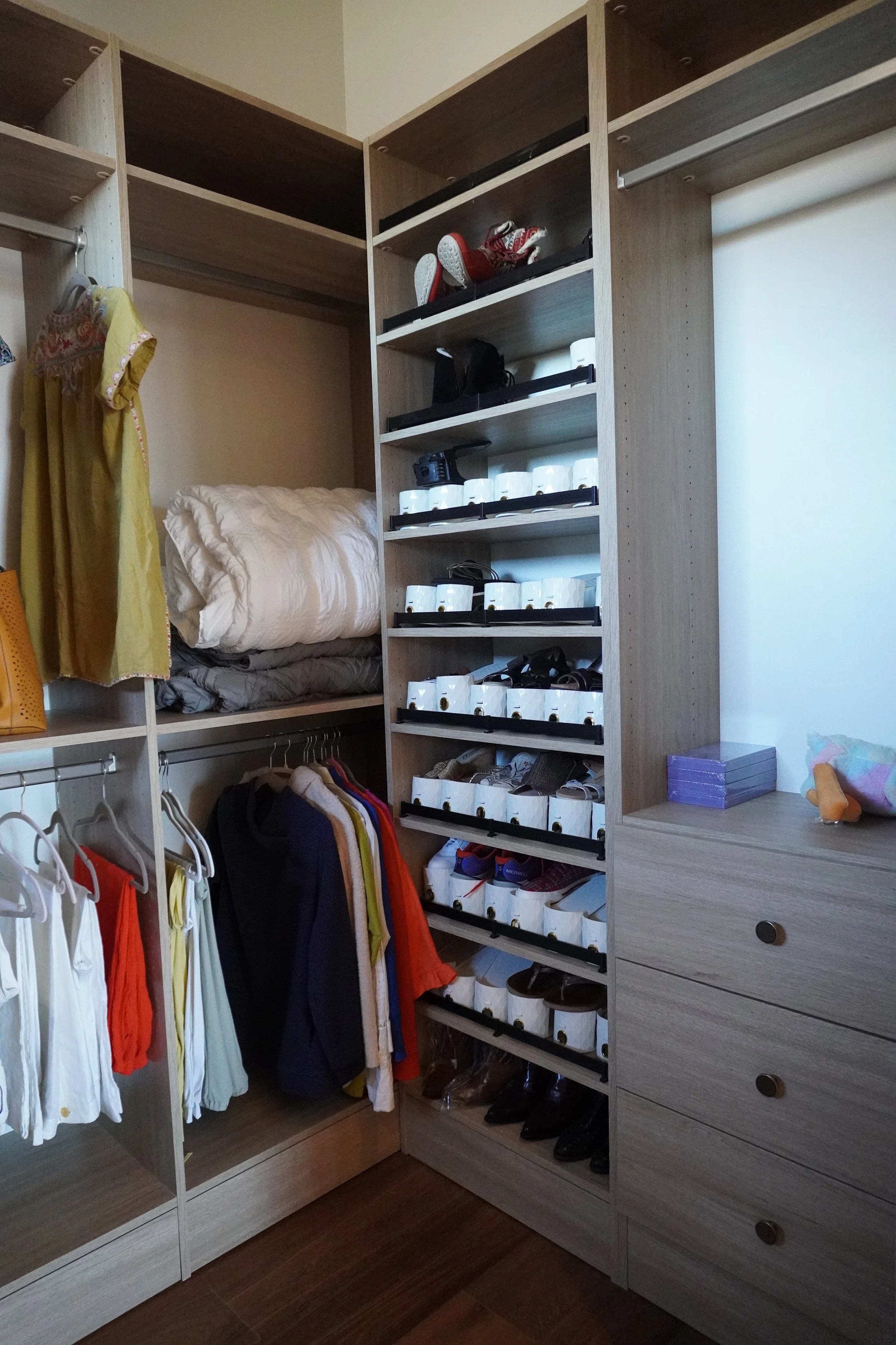 An organized walk-in closet with shelves, hanging clothes, shoes, and miscellaneous items.