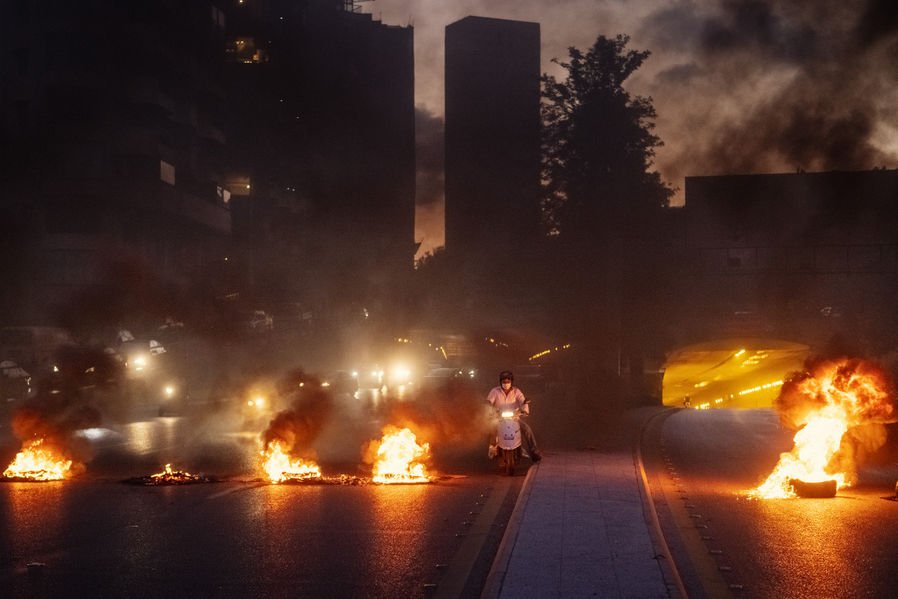  A civilian on a motorbike is traversing a road block set up by protesters in Beirut, Lebanon against the worsening living conditions in the country. 