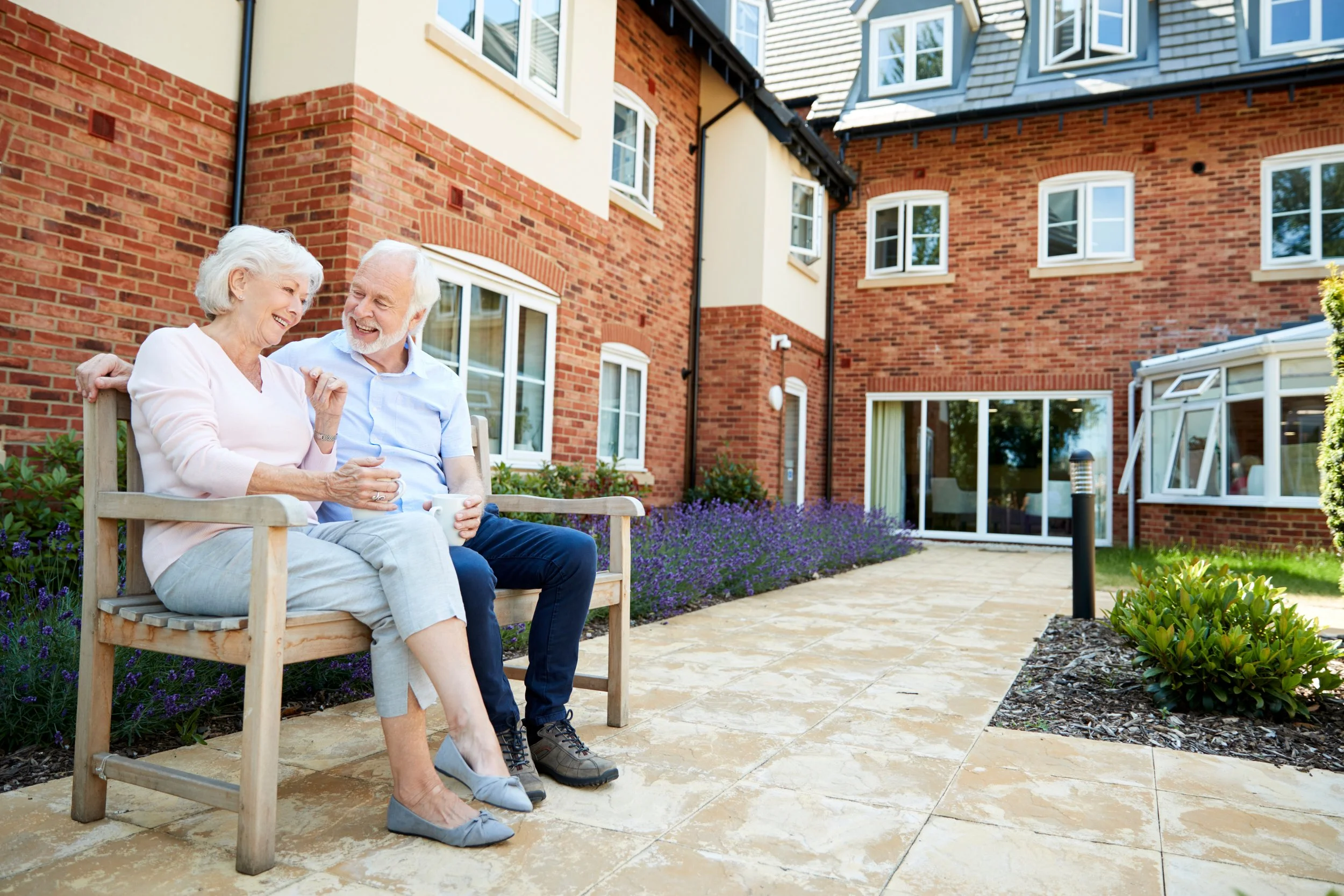 Elderly couple sitting in front of assisted living center.