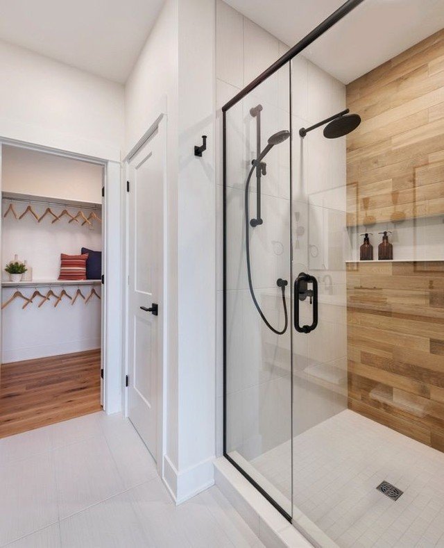 The spacious primary ensuite is designed with sleek, luxurious black finishes that stand out beautifully against the light wood vanity and white tones. Adding texture adds an elevated style to this new home and these finishes are sought after by many