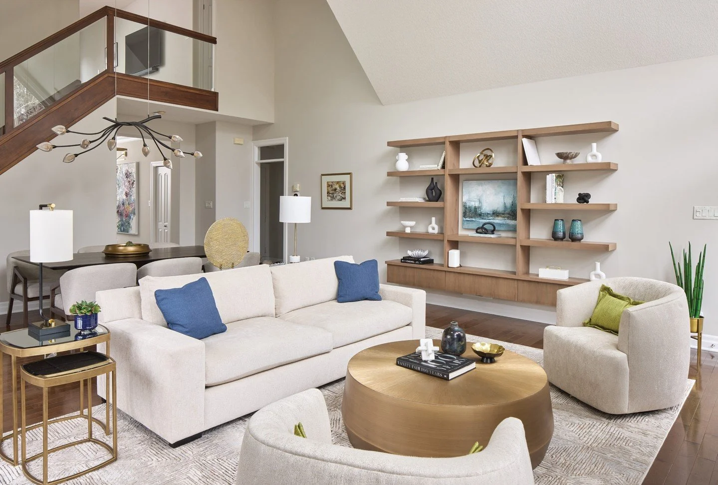 Design Inspiration: Floating wood shelving adds warmth and visual interest to the great room while allowing decorative objects and art to have a moment. Matte gold tones on the round coffee table, nesting tables and select accessories create understa
