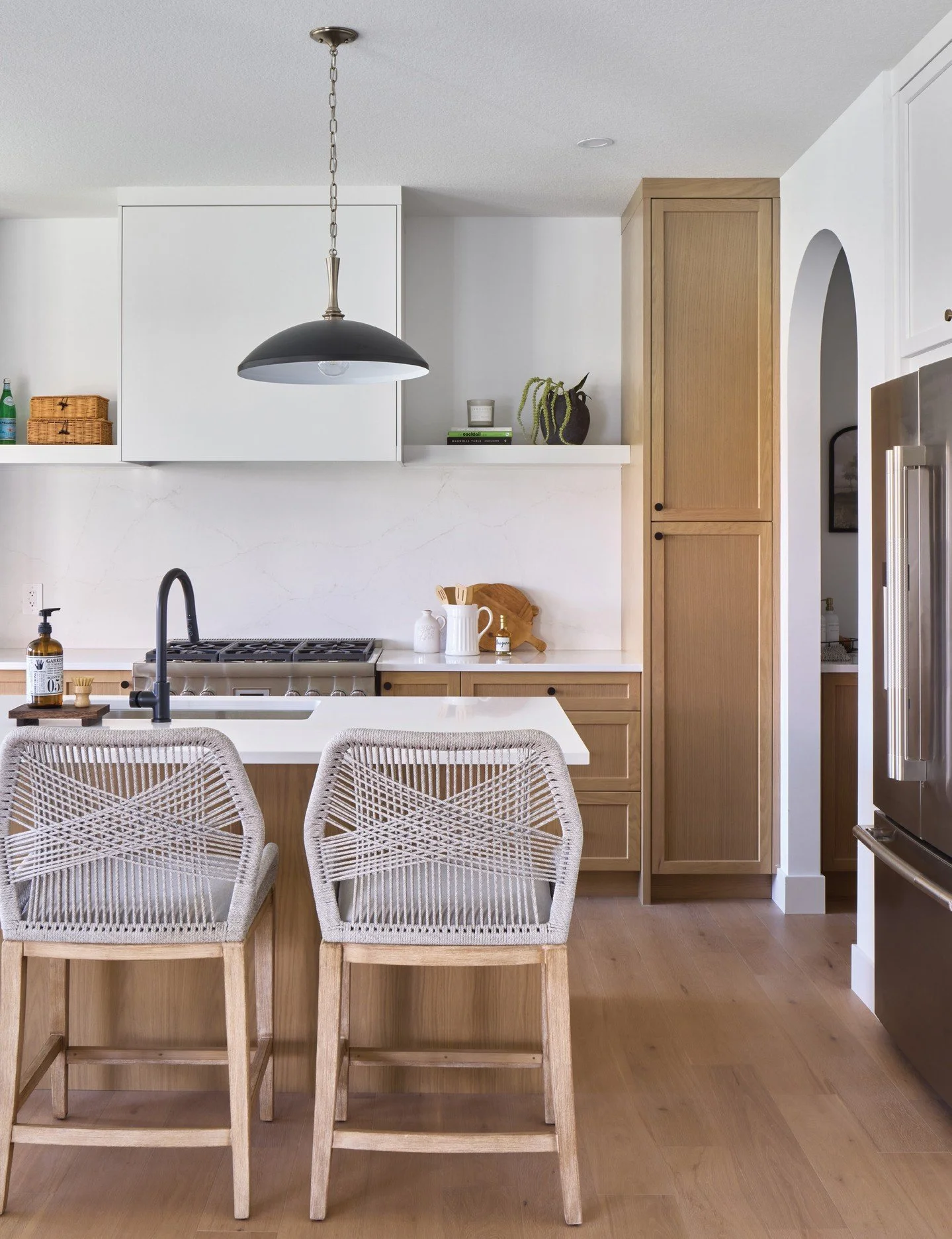 Note the design elements used in this sleek kitchen. A single slab backsplash and a custom range hood flanked by open shelving give the back kitchen wall a crisp, tailored look. Black accents, repeated in the fixtures, hardware and d&eacute;cor, crea