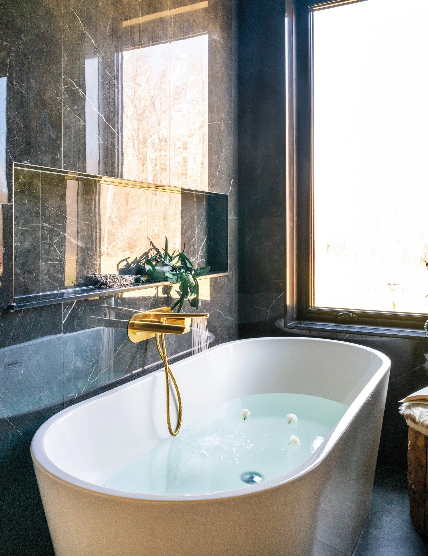 Within the walls of this custom farmhouse in Simcoe County, the homeowners chose specific design elements with their builder that brought their vision to life. To create the spa-like sanctuary, black slab tiles and a brass faucet above the soaker tub