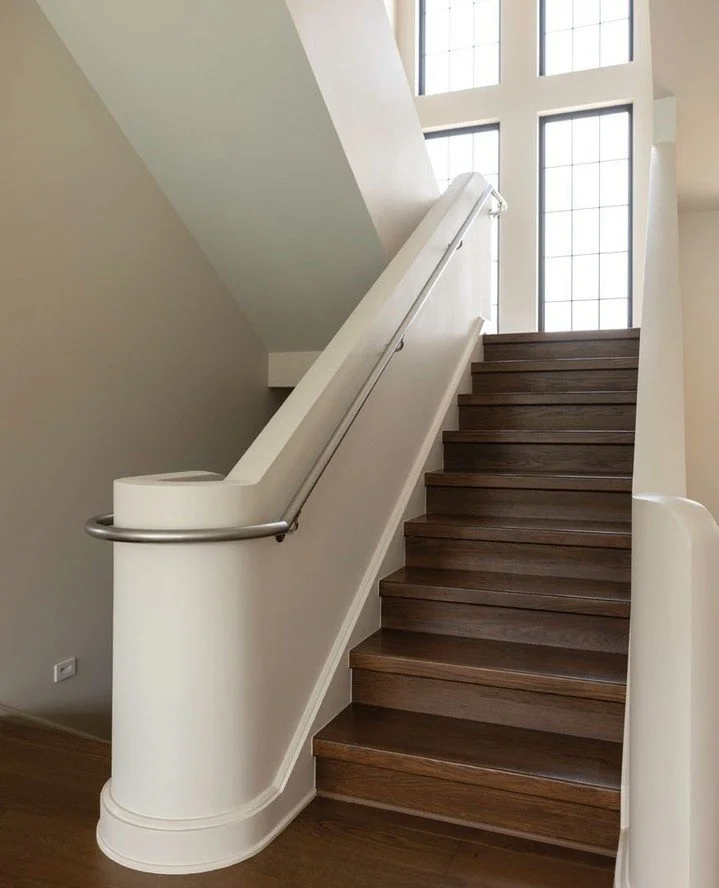 A sculptural staircase is a striking focal point on the main floor. The staircase&rsquo;s curves are repeated in the living room armchairs, while the marble coffee table echoes the nearby kitchen island. Be inspired by the attention to detail and fin