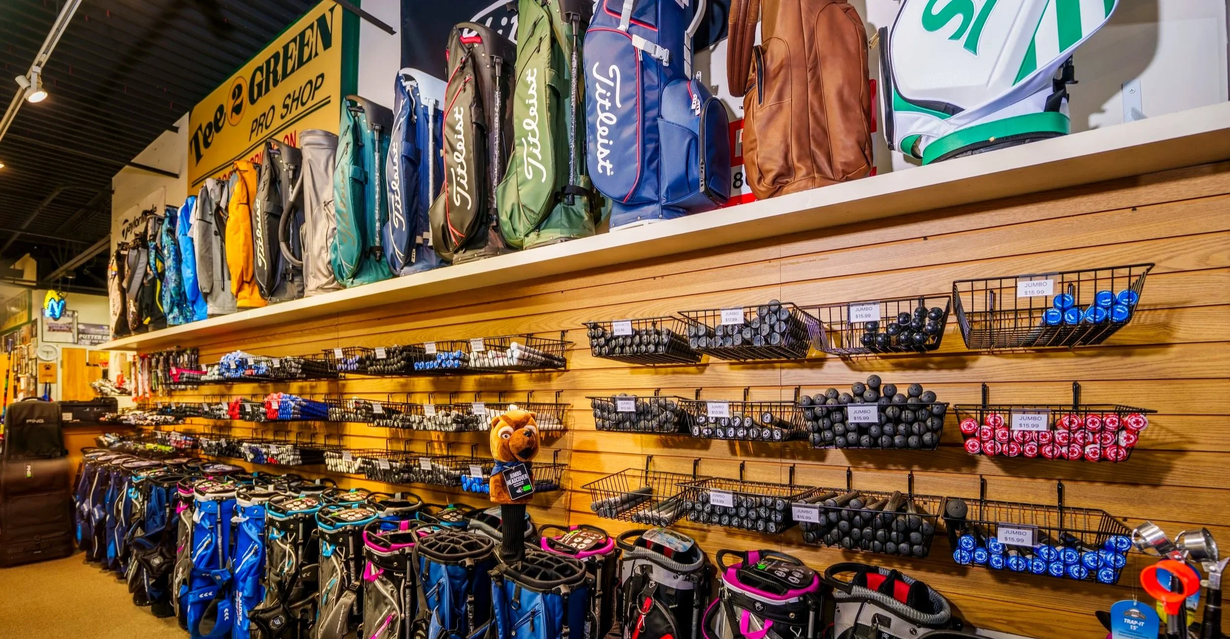 Golf bags and golf equipment displayed on shelves at a sporting goods store.