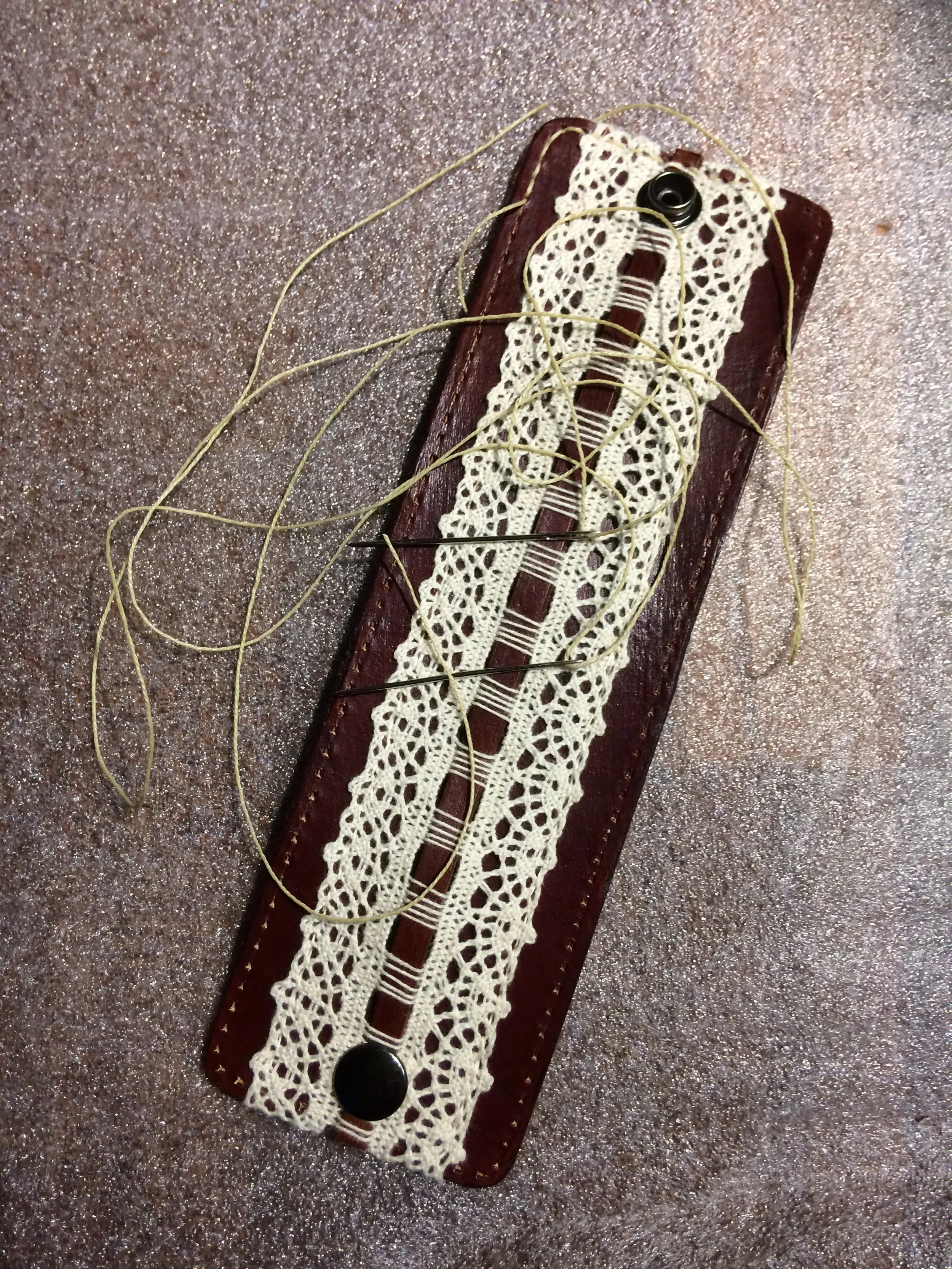 Leather Wristband: 2.5 inches wide, medium brown with lace detail; leather lined. Shows stitching process.