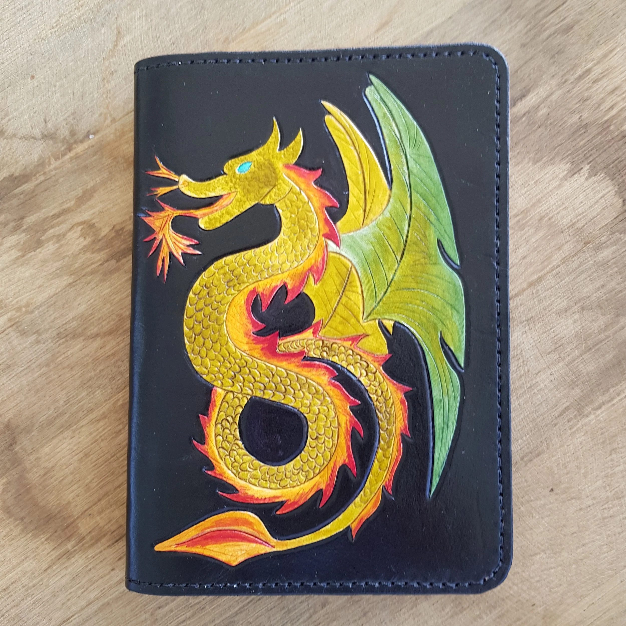 Winged Serpent.jpg  Winged serpent in green, orange and yellow on a black vegetable tanned leather refillable notebook cover.