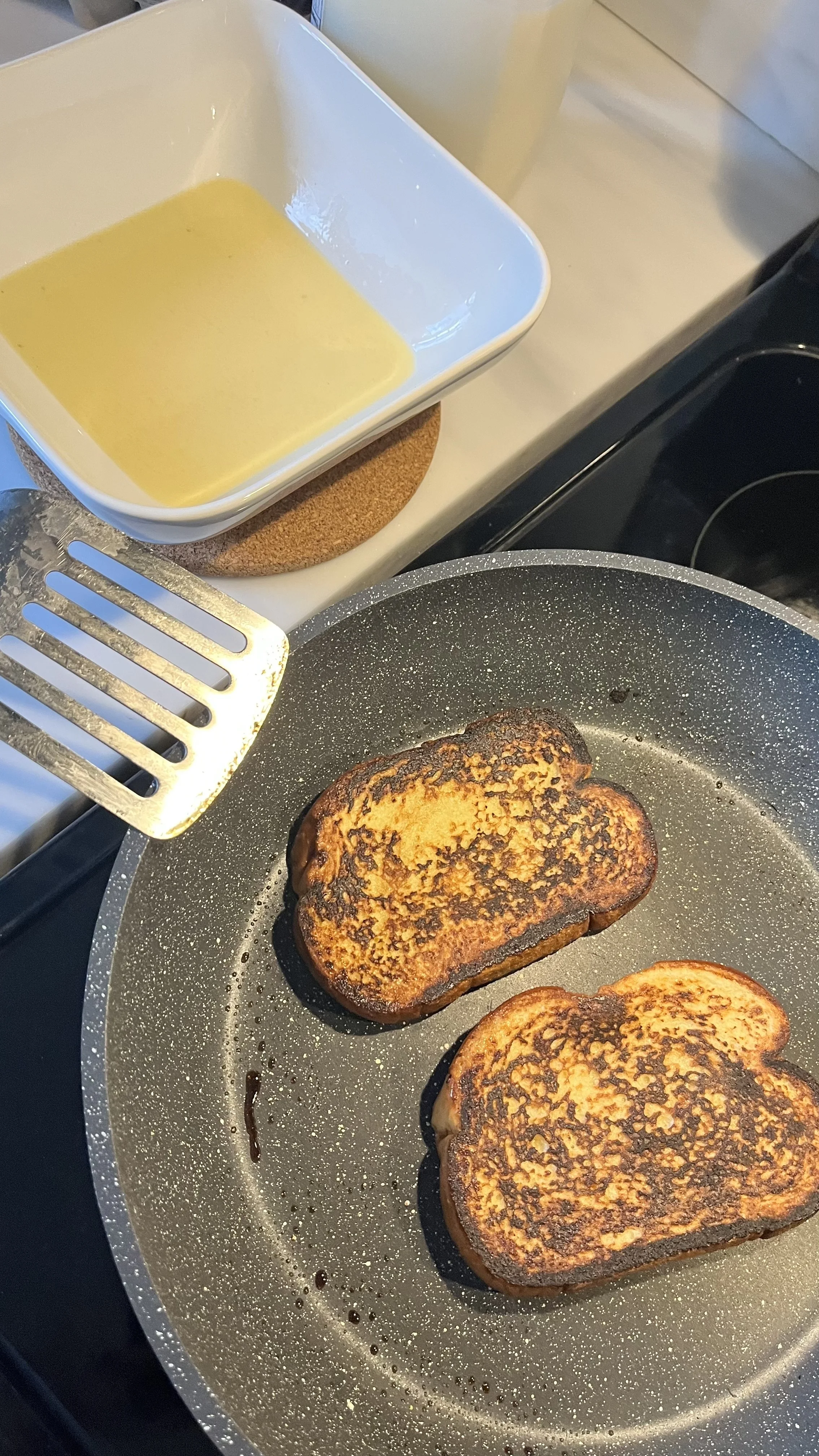 Two pieces of French toast being cooked in a frying pan.