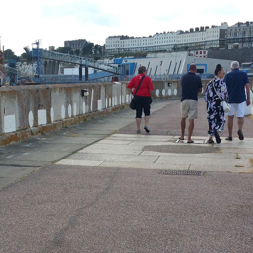 visitors walk past the chalk Morse code on the harbour arm