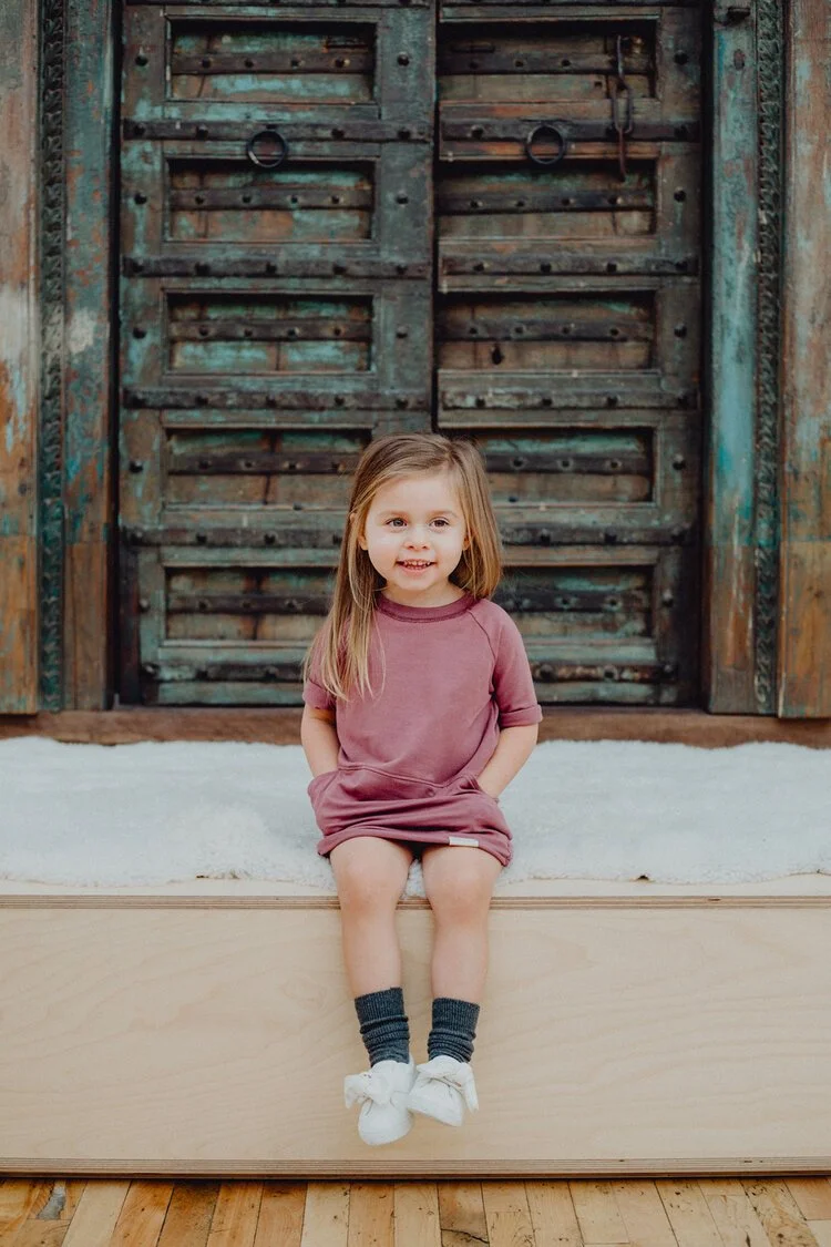 Fillette assise à l'extérieur avec une robe rose