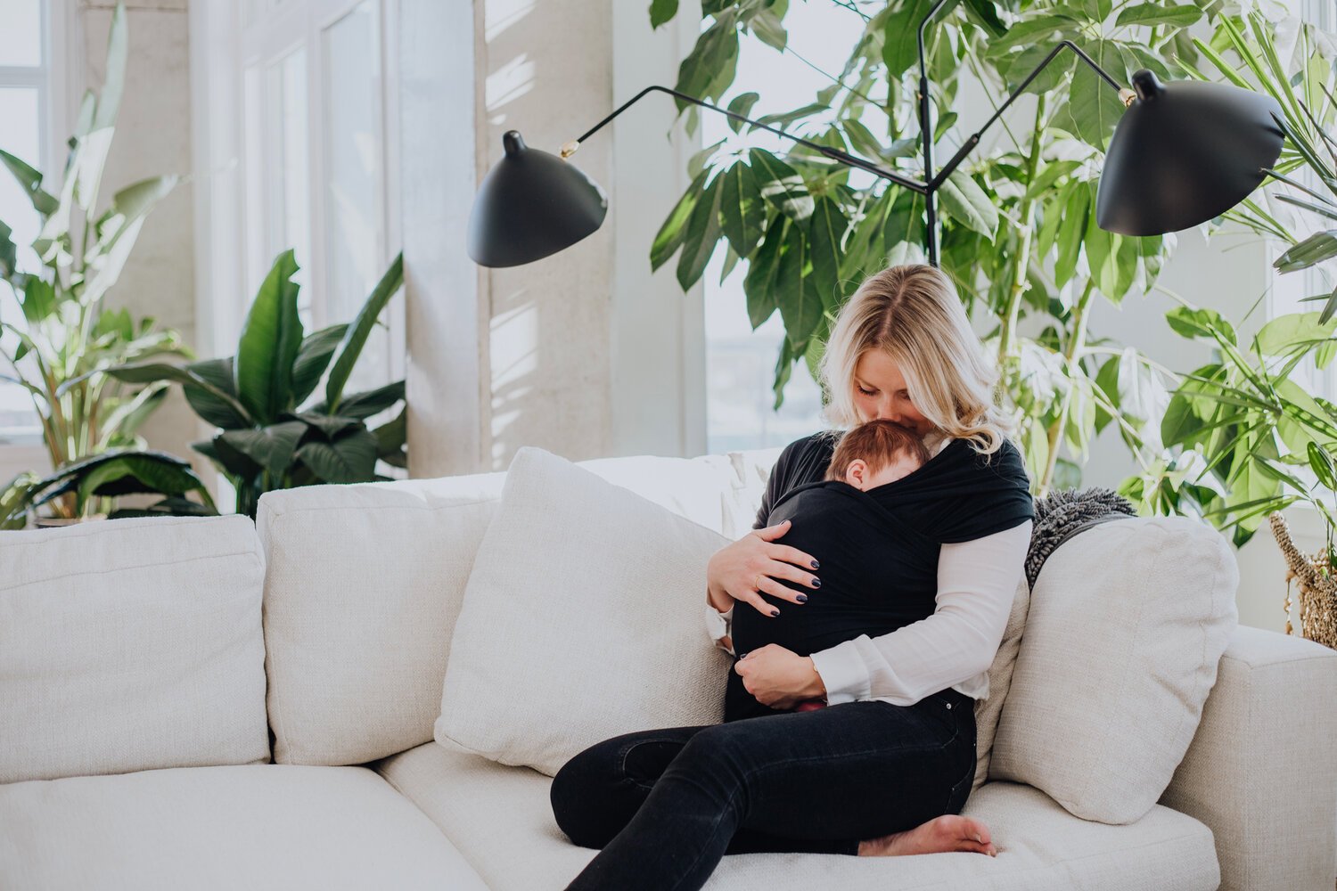 Maman avec son bébé emmailloté sur un sofa