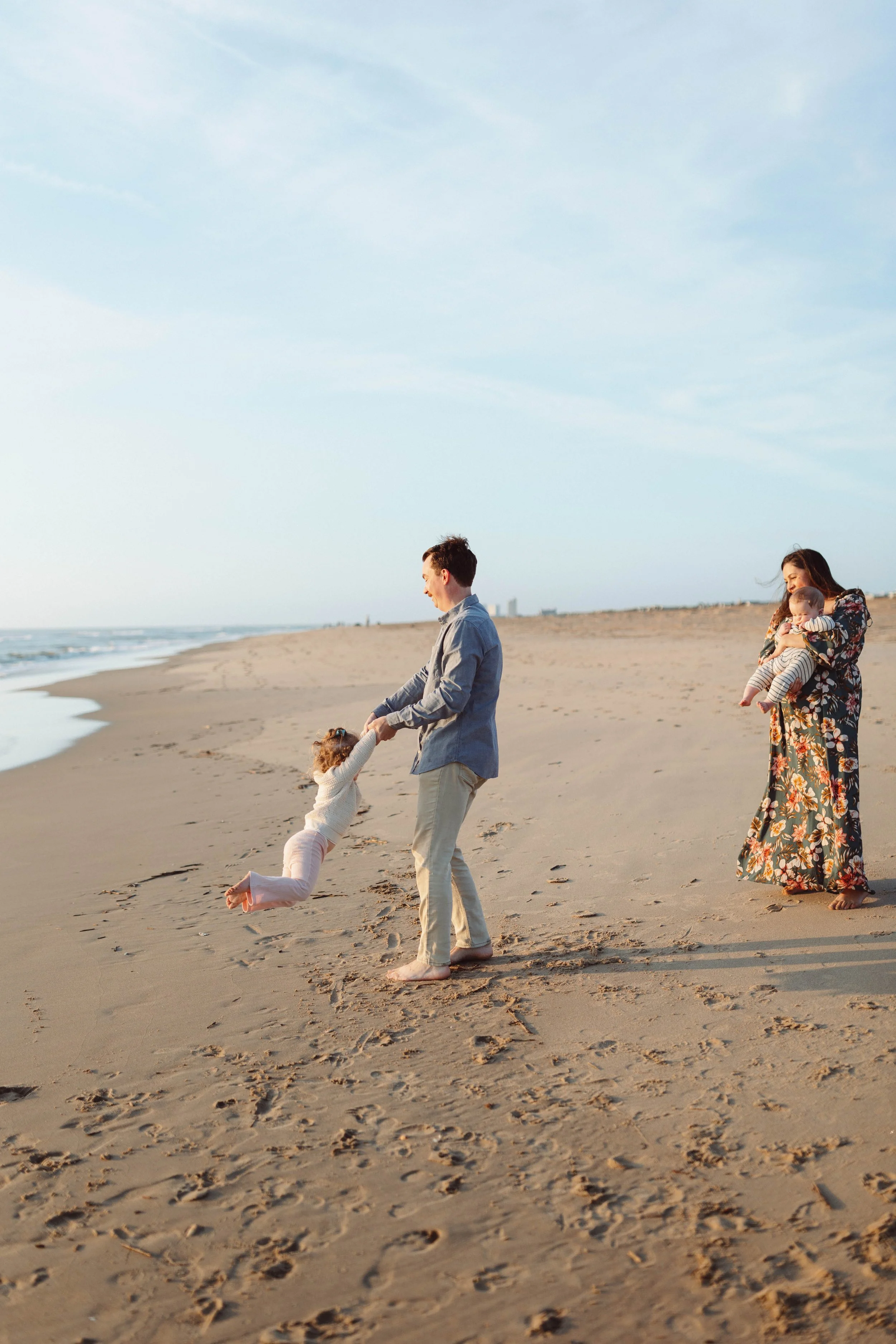 family laughing on the beach smiling spinning children around